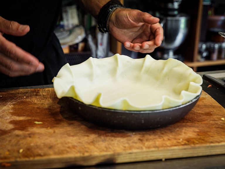 Schritt 2: Den Kuchen- oder Mürbeteig in eine passende Kuchenform legen, der Teig soll über den Rand hinausragen Schritt 2: Den Kuchen- oder Mürbeteig in eine passende Kuchenform legen, der Teig soll über den Rand hinausragen