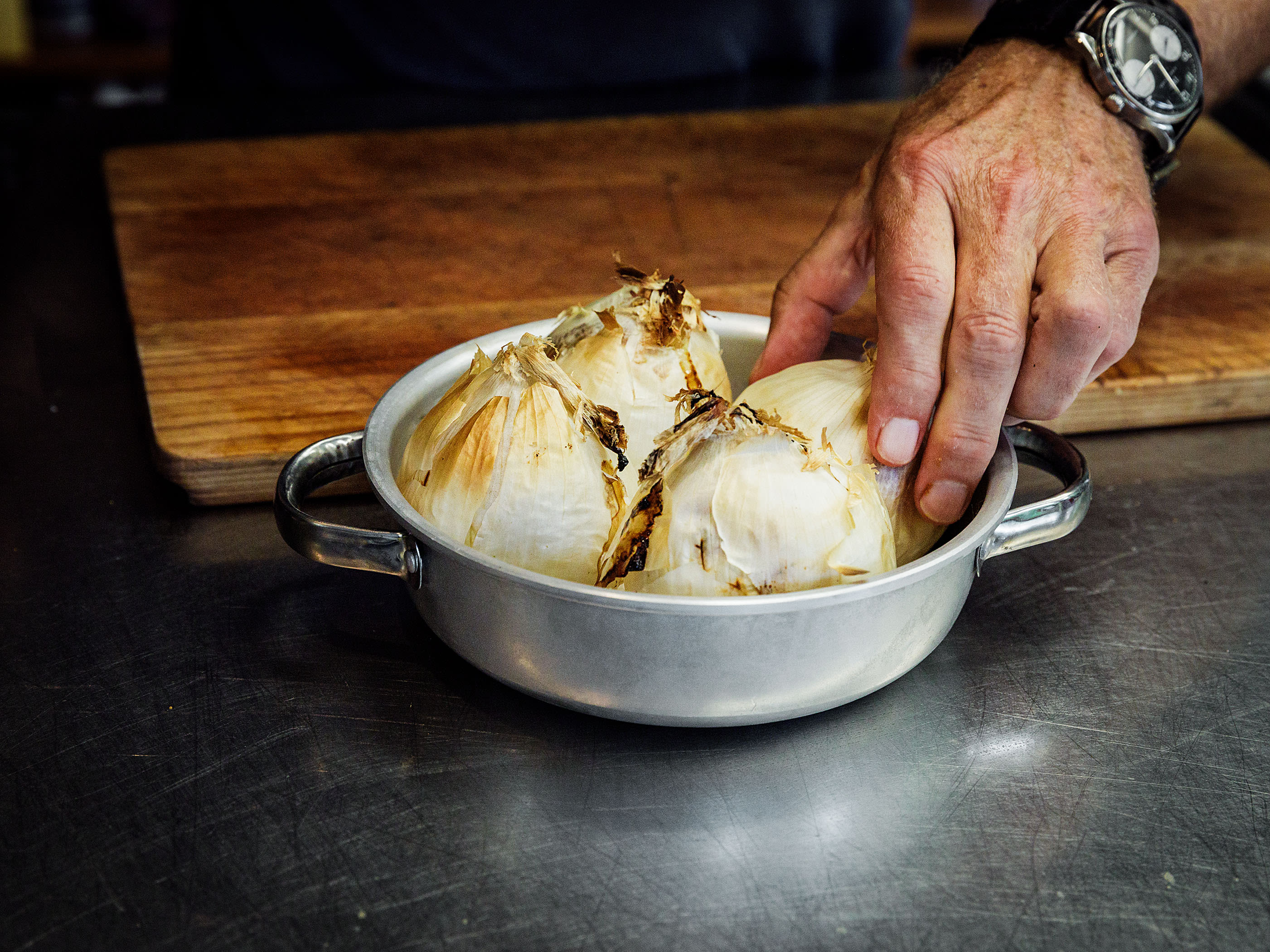 Schritt 1: Eine ofenfeste Form, in der vier Zwiebeln gerade Platz haben, mit grobem Salz ausstreuen und die ungeschälten Zwiebeln mit der Wurzel nach unten hineinsetzen und backen
