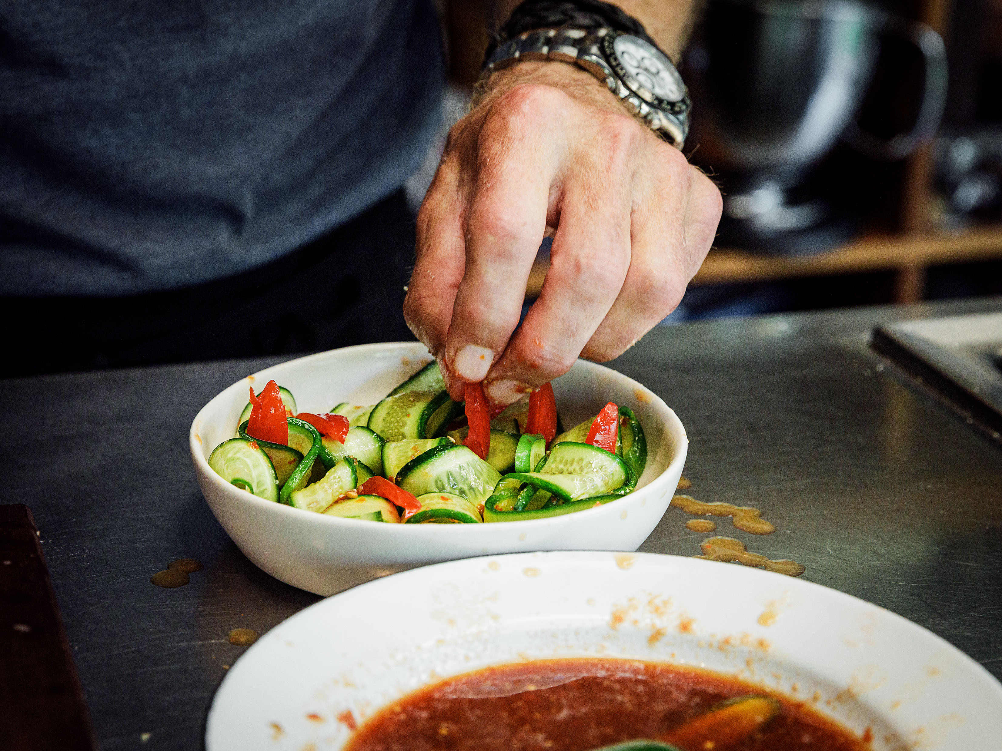 Schritt 2: Den Gurkensalat mit Peperoncini, Korianderkresse, Cherrytomaten und farbigen Blüten dekorieren