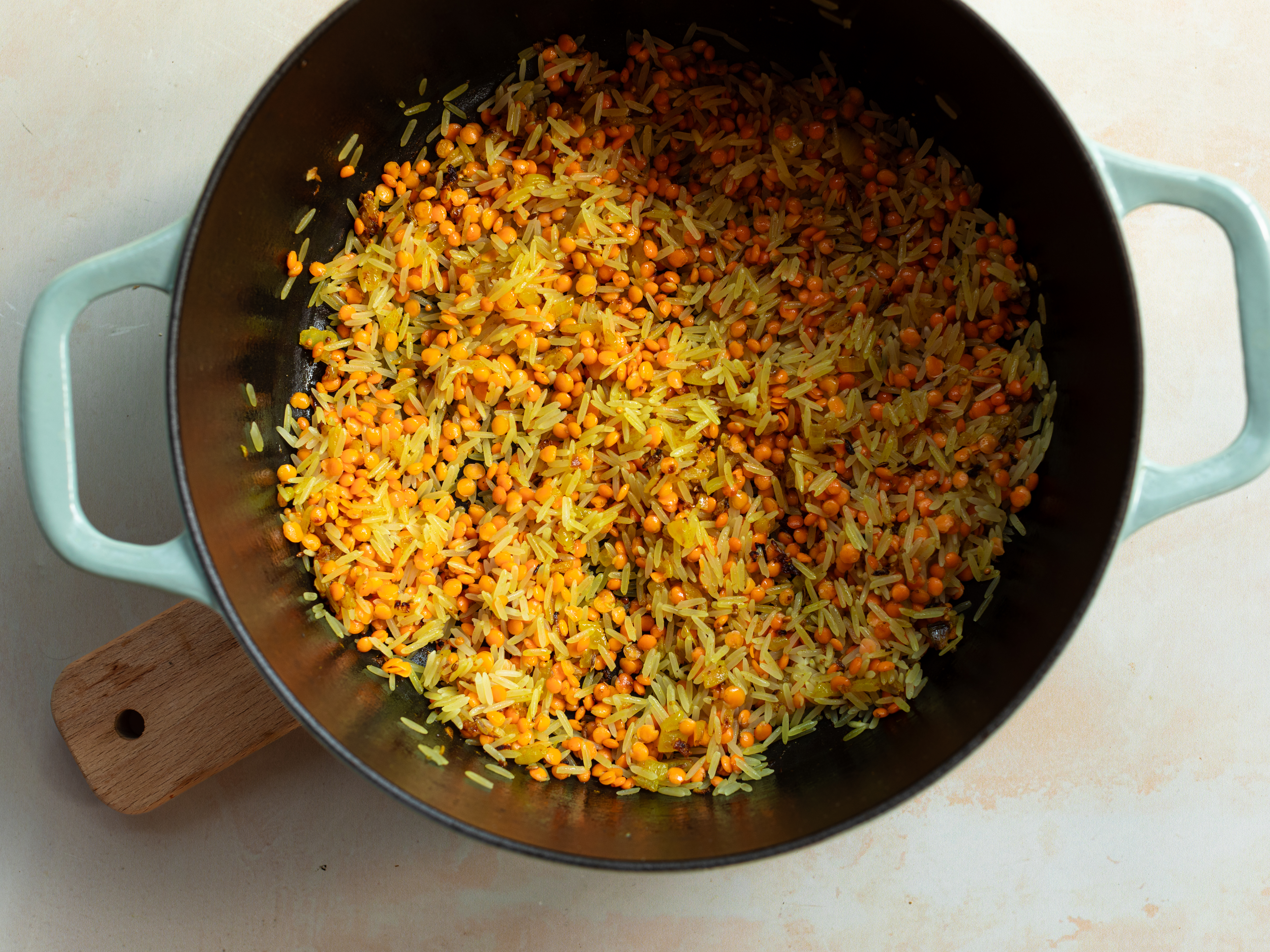 Schritt 3: Den gewaschenen Reis und die Linsen in den Topf geben und unter ständigem Rühren anbraten, bis sie leicht geröstet sind