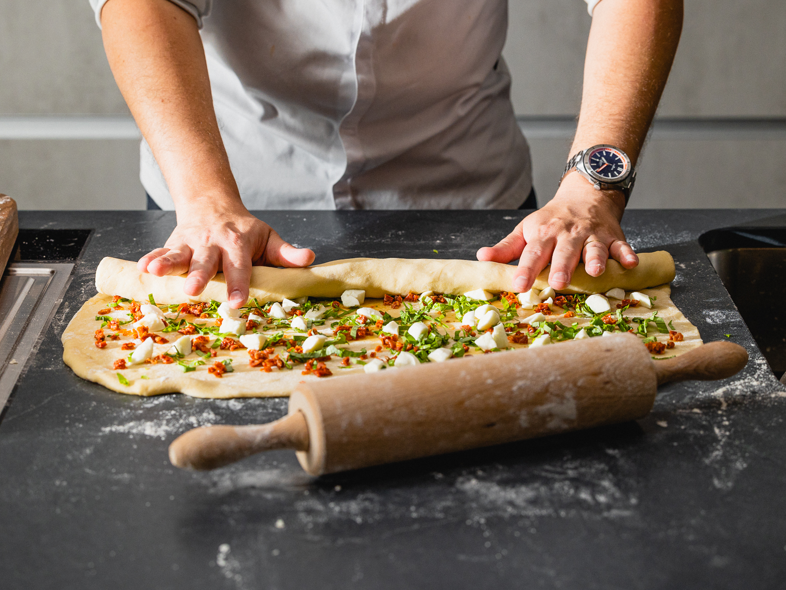 Schritt 2: Den Teig von der langen Seite her aufrollen und in der Mitte längs durchschneiden.  