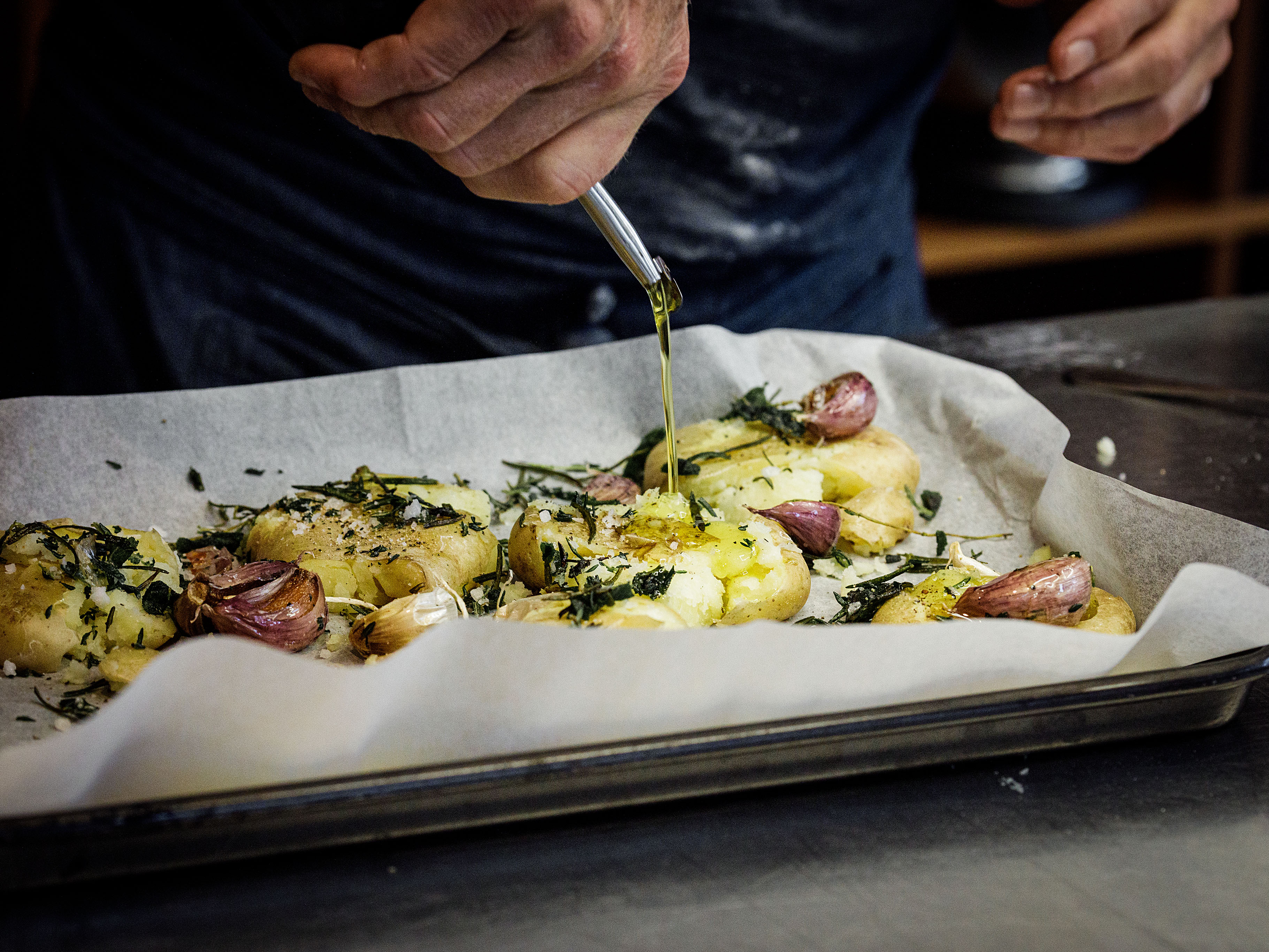 Schritt 2: Kartoffeln mit Olivenöl, Salz und Pfeffer sowie Thymianzweig und Knoblauchzehen grosszügig beträufeln