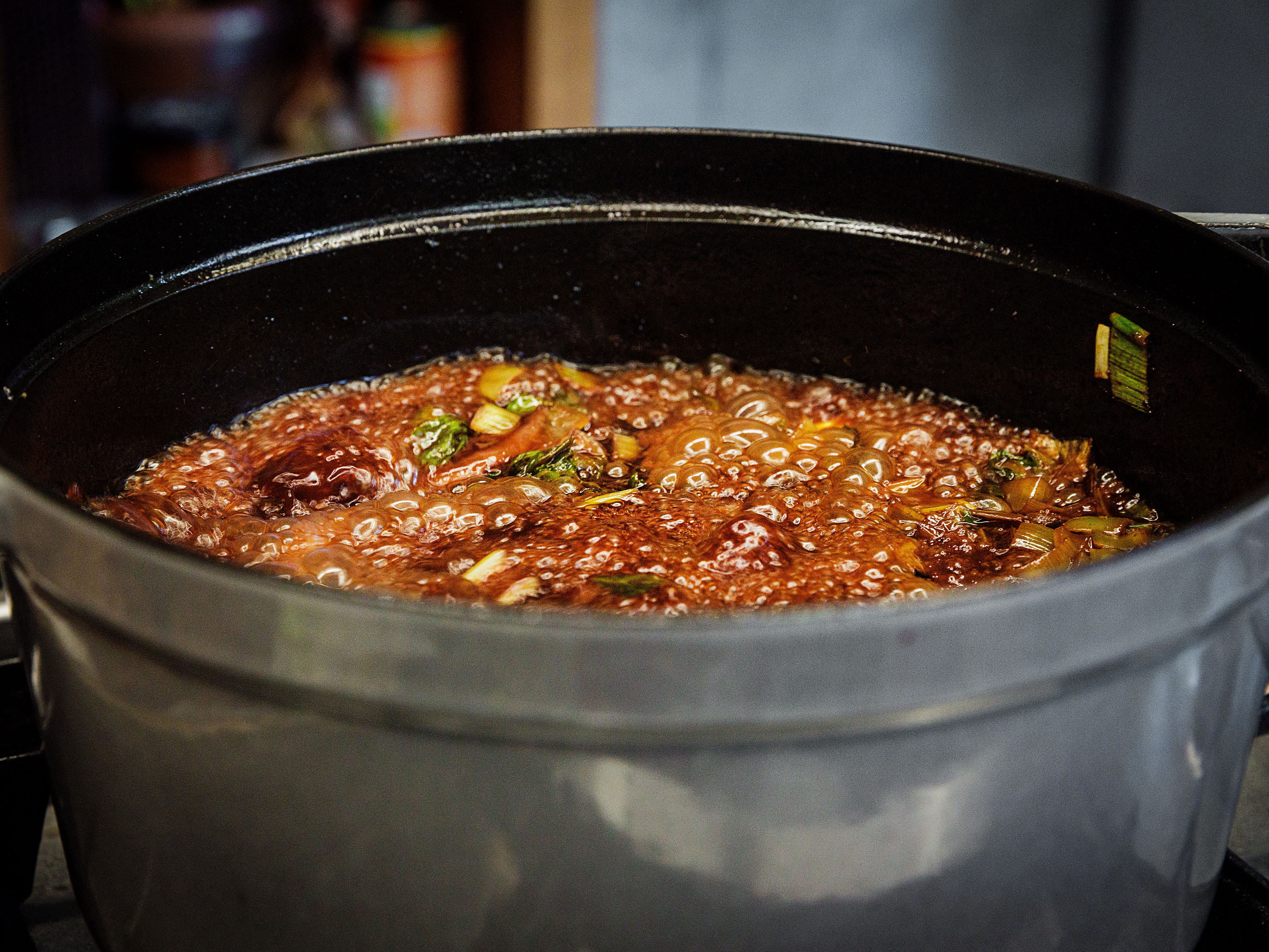 Schritt 3: Kalbsfuss-Scheiben zugeben, mit Rotwein und Portwein ablöschen, Gewürze und Kräuter zugeben und leicht einkochen lassen