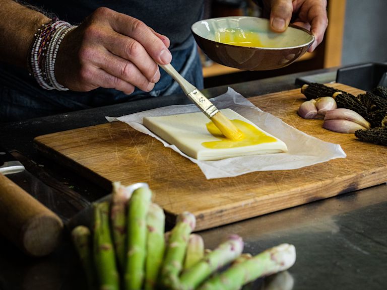 Schritt 1: In einer kleinen Schüssel das Eigelb mit einigen Tropfen kaltem Wasser verrühren und die Blätterteig-Rechtecke damit bestreichen Schritt 1: In einer kleinen Schüssel das Eigelb mit einigen Tropfen kaltem Wasser verrühren und die Blätterteig-Rechtecke damit bestreichen
