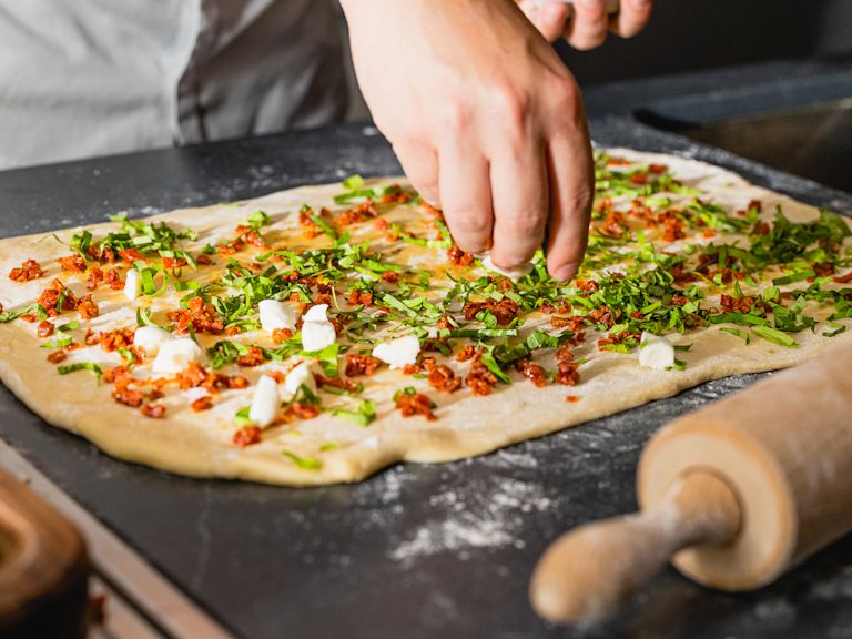 Schritt 1: Den Teig auf einer bemehlten Arbeitsfläche zu einem Rechteck ausrollen und die Tomaten, den Mozzarella und den Basilikum darauf verteilen. Schritt 1: Den Teig auf einer bemehlten Arbeitsfläche zu einem Rechteck ausrollen und die Tomaten, den Mozzarella und den Basilikum darauf verteilen.