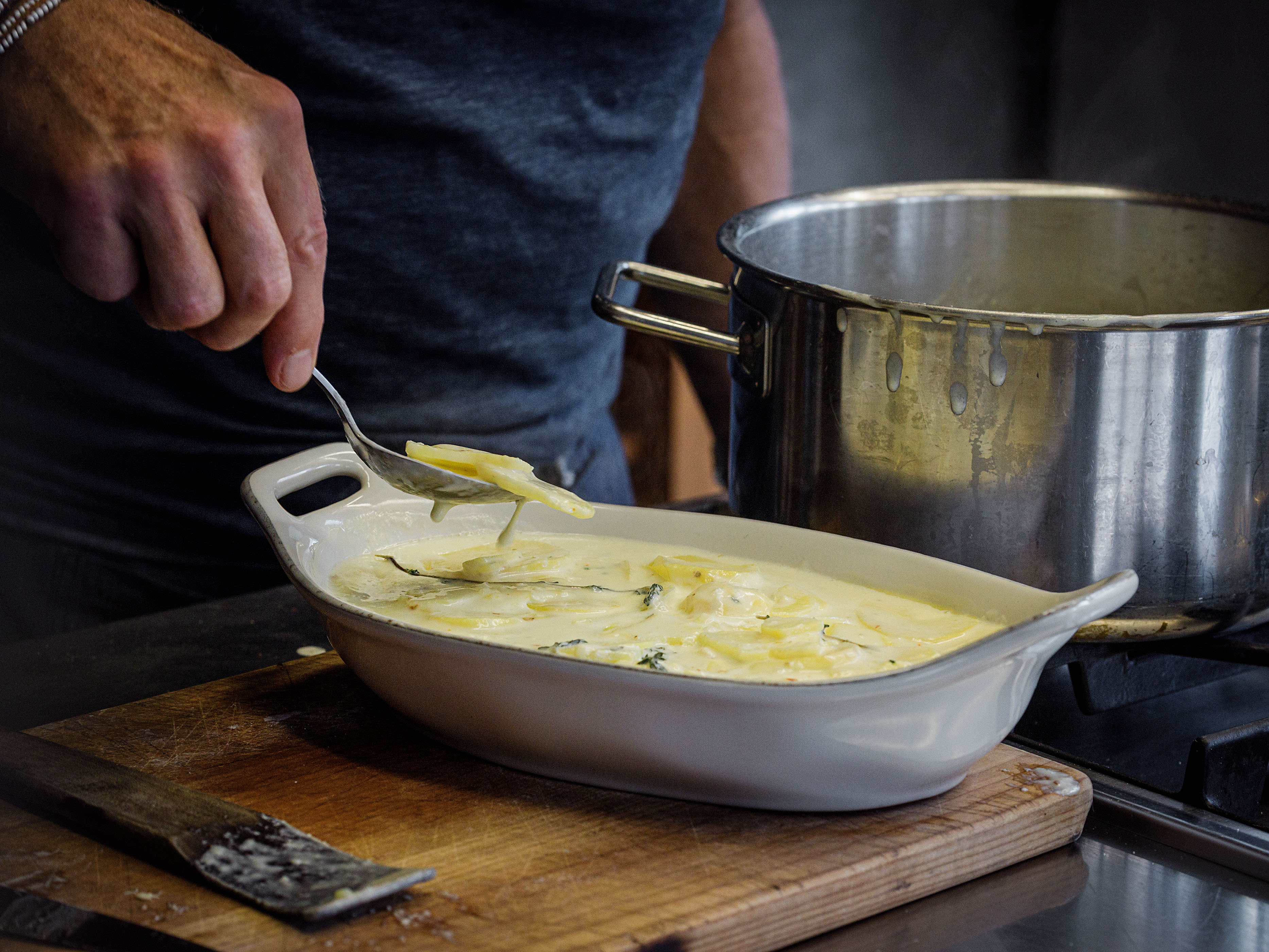 Schritt 2: Eine weite, feuerfeste Form ausbuttern und die Kartoffelscheiben zusammen mit der Rahm-Milch-Sauce möglichst flach einschichten;