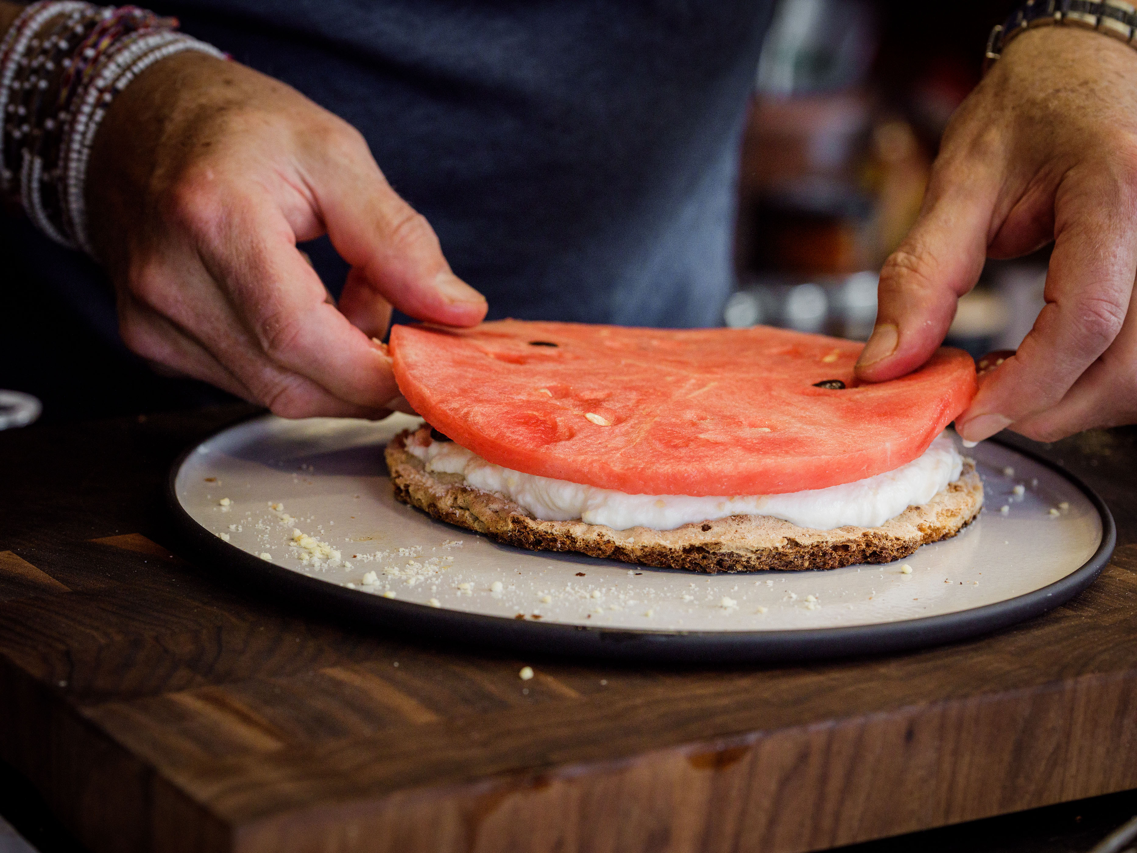 Schritt 4: Ein Drittel des Rosen-Schlagrahms gleichmässig auf die unterste Dacquoise-Scheibe streichen, mit Mandelmehl bestreuen und mit einer Wassermelonenscheibe bedecken.