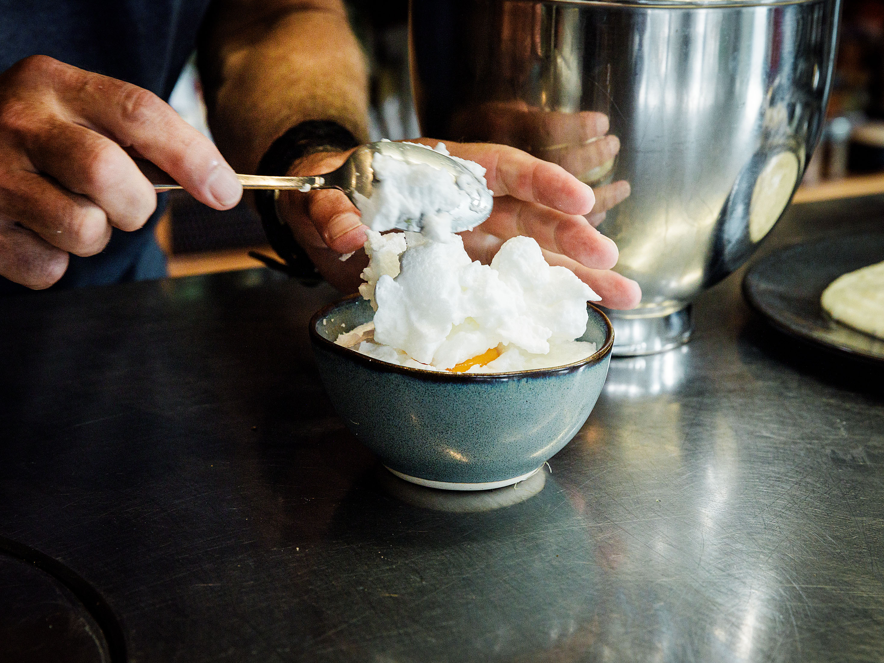 Schritt 2: Die Hälfte des geschlagenen Eiweisses bis zum oberen Rand einfüllen und eine Vertiefung eindrücken, dann je ein Eigelb vorsichtig hineingeben und mit dem restlichen Eiweiss bedecken