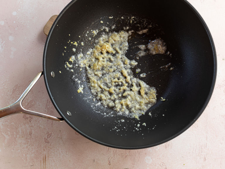 Schritt 3: In einem Wok das Sesamöl erhitzen, dann den gehackten Knoblauch und den geriebenen Ingwer hinzufügen und kurz anbraten
