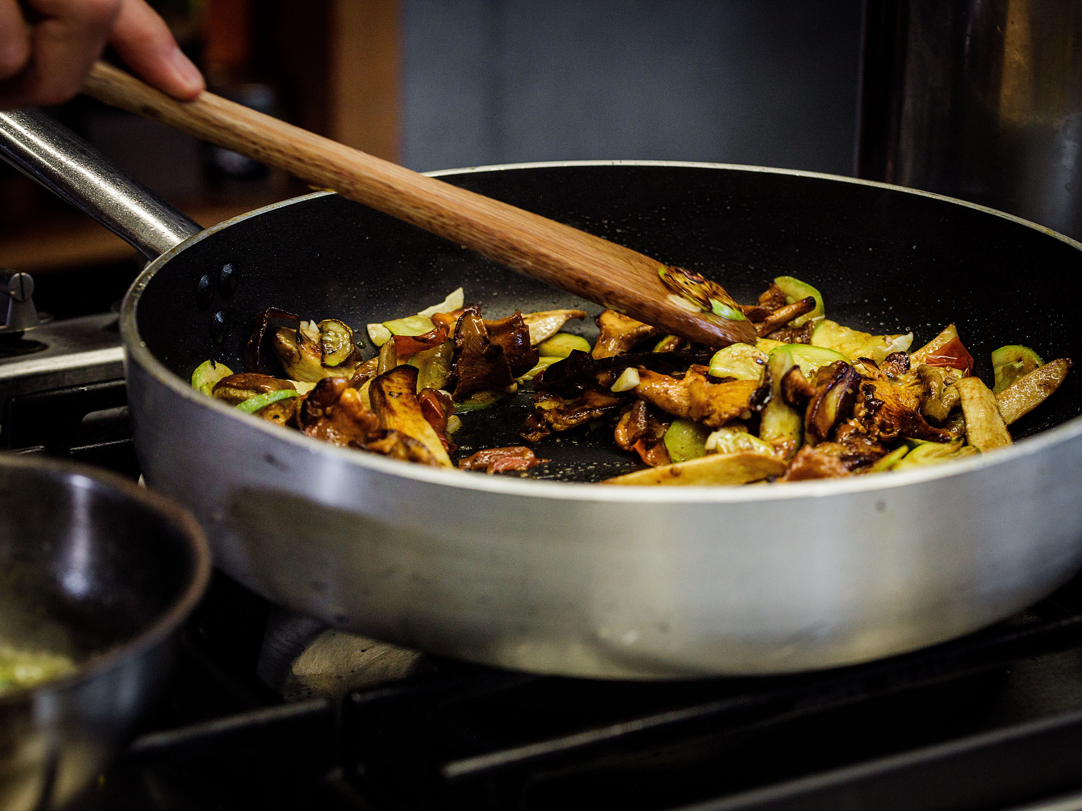 Schritt 2: Zucchini und, falls verwendet, die Zucchiniblüten mit Olivenöl zu den Pilzen geben und auf hoher Hitze anbräunen