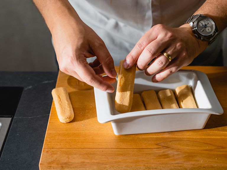 Schritt 2: Eine Form mit Löffelbisquits auslegen, mit Orangen-Kaffee beträufeln und mit einer Schicht Mousse bedecken. Schritt 2: Eine Form mit Löffelbisquits auslegen, mit Orangen-Kaffee beträufeln und mit einer Schicht Mousse bedecken.