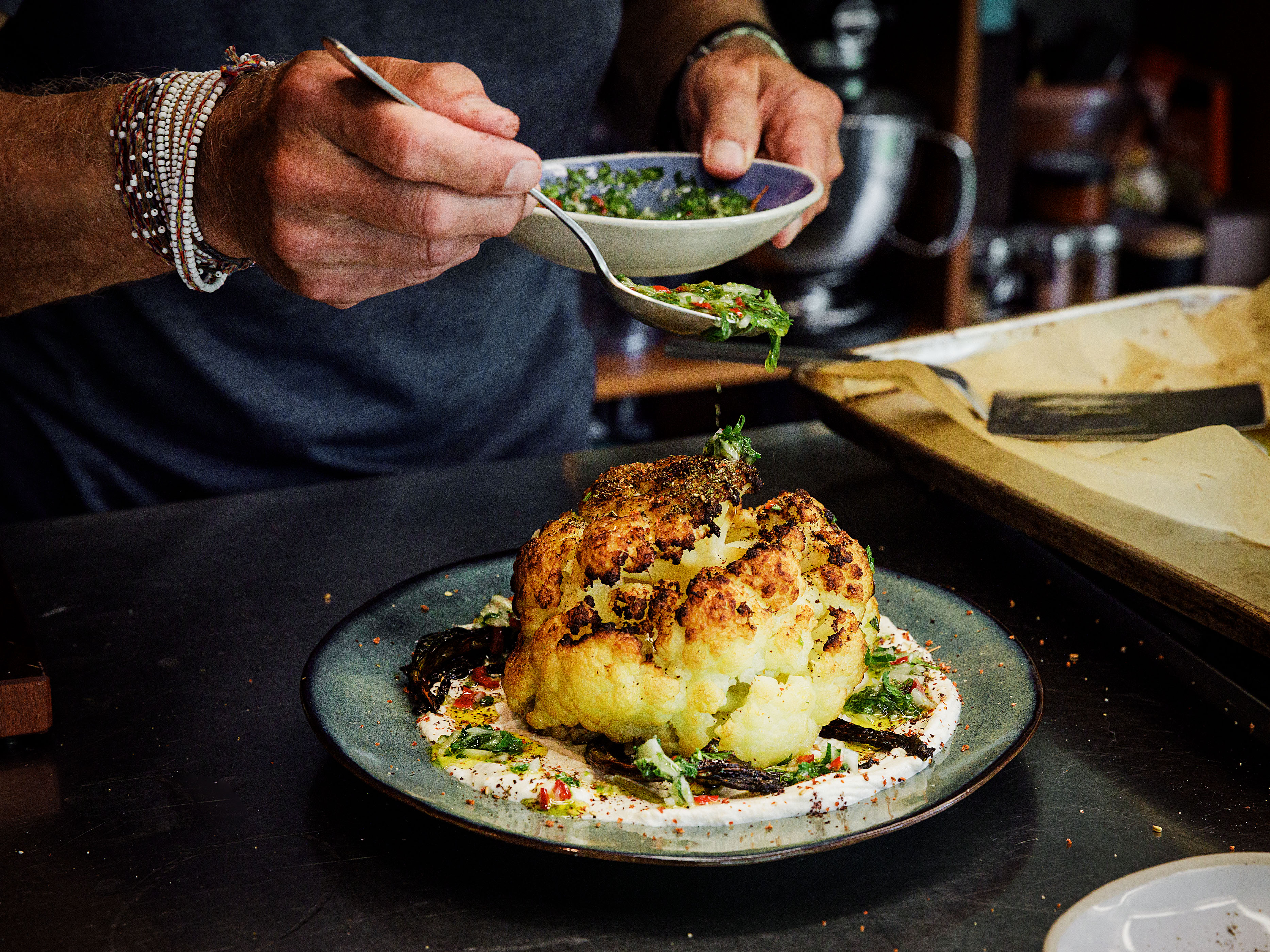 Schritt 3: Die Joghurt-Tahin-Sauce auf einem grossen Teller verteilen, den Blumenkohl darauf anrichten, mit der Chili-Vinaigrette umgiessen und mit Dukkah bestreuen