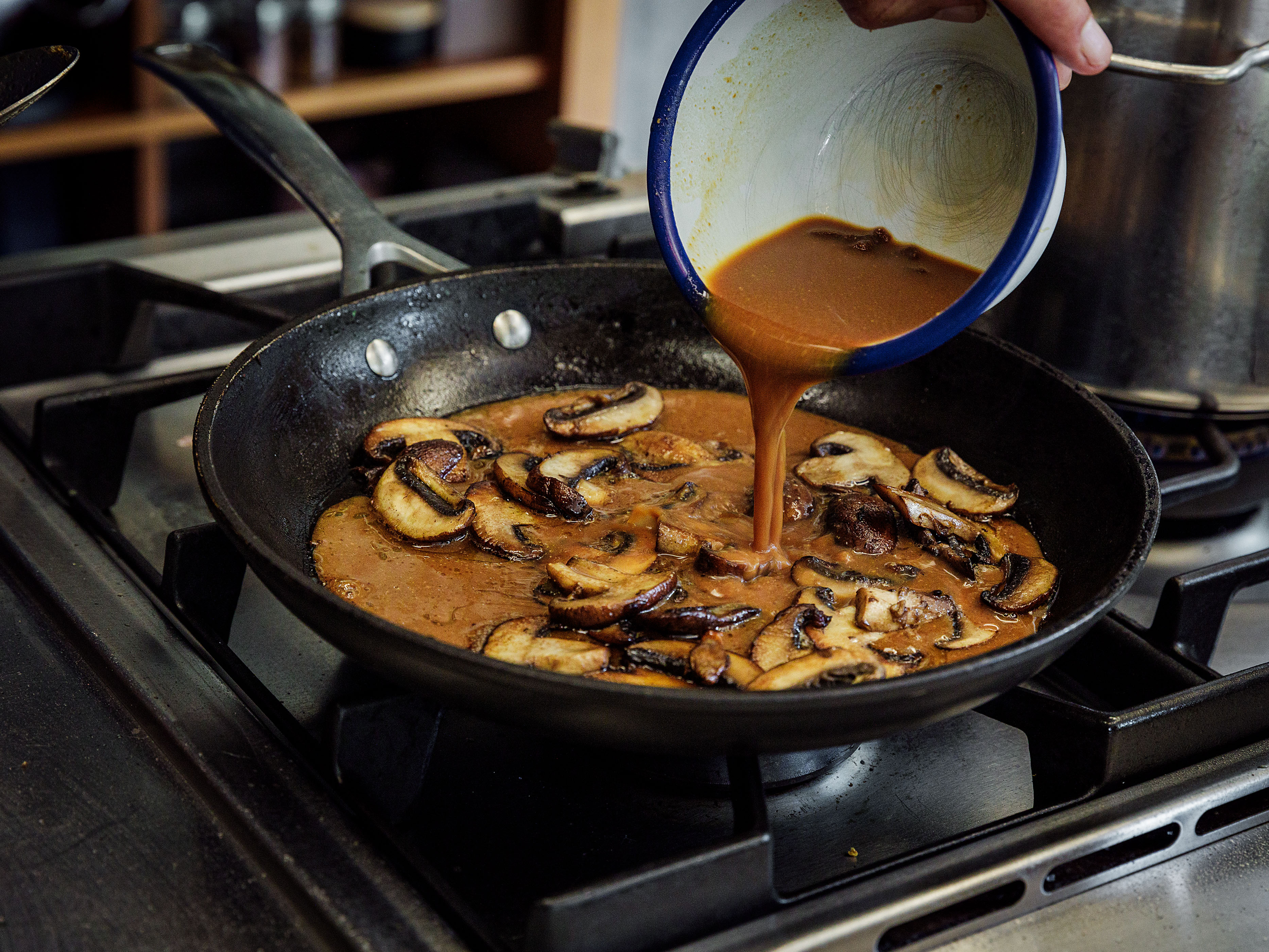 Schritt 2: Sobald die Champignons knusprig angebraten sind, vom Feuer nehmen, die Misopaste-Pastawasser-Mischung in die Pfanne geben, umrühren und etwas einkochen lassen
