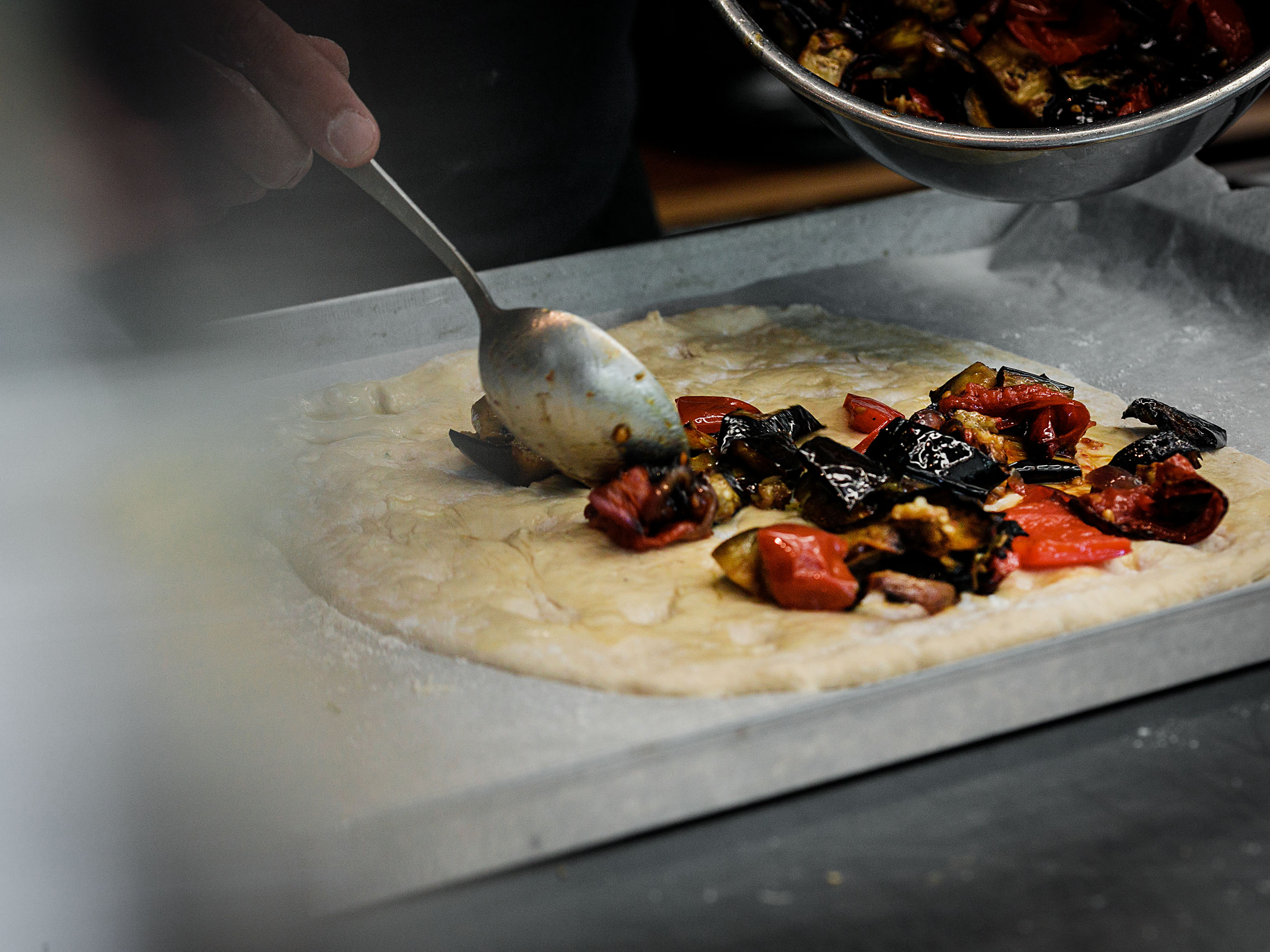 Schritt 4: Den ausgerollten Teig mit Olivenöl bepinseln und mit einer gleichmässigen Schicht mit den Gemüsestücken belegen