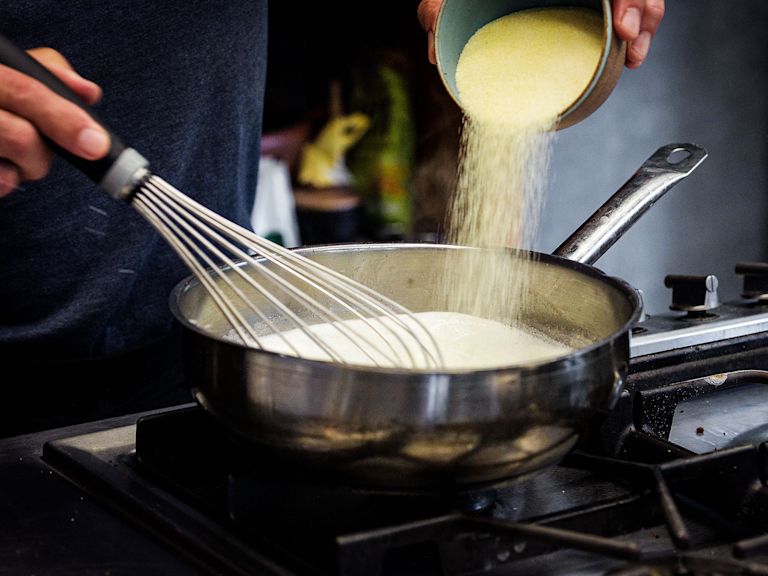 Schritt 1: Hartweizengriess unter ständigem Rühren mit einem Schwingbesen langsam einrühren Schritt 1: Hartweizengriess unter ständigem Rühren mit einem Schwingbesen langsam einrühren