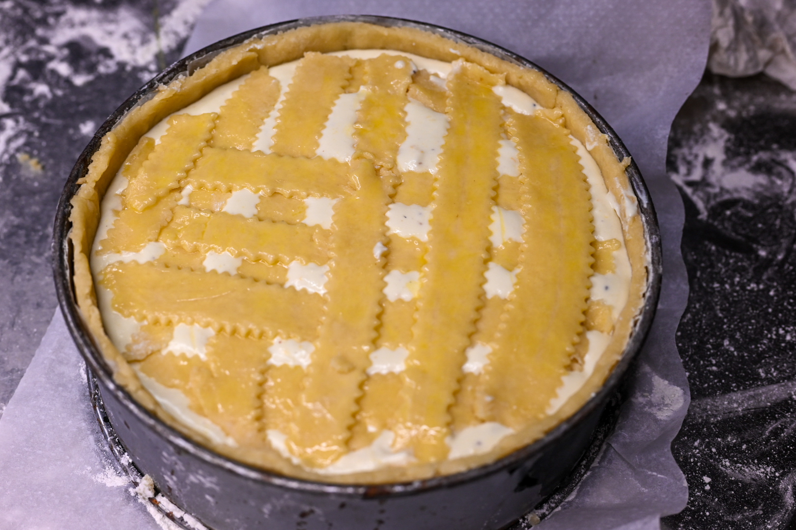 Schritt 3: Die Teigstreifen vorsichtig gitterförmig darauf verteilen und den überstehenden Teig abschneiden