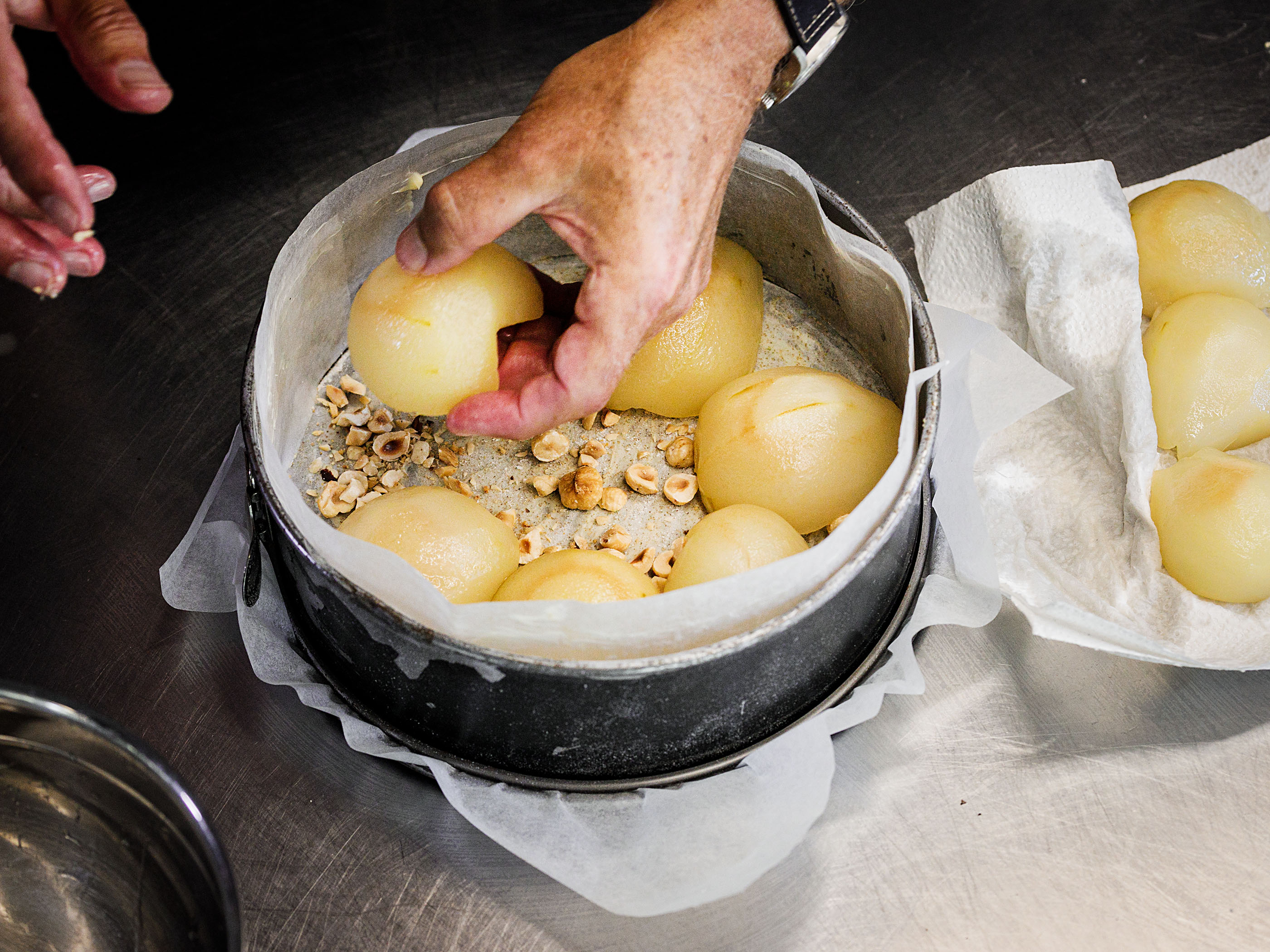 Schritt 2: Die Birnenhälften mit der Schnittseite nach unten auf den Haselnüssen in der Form arrangieren