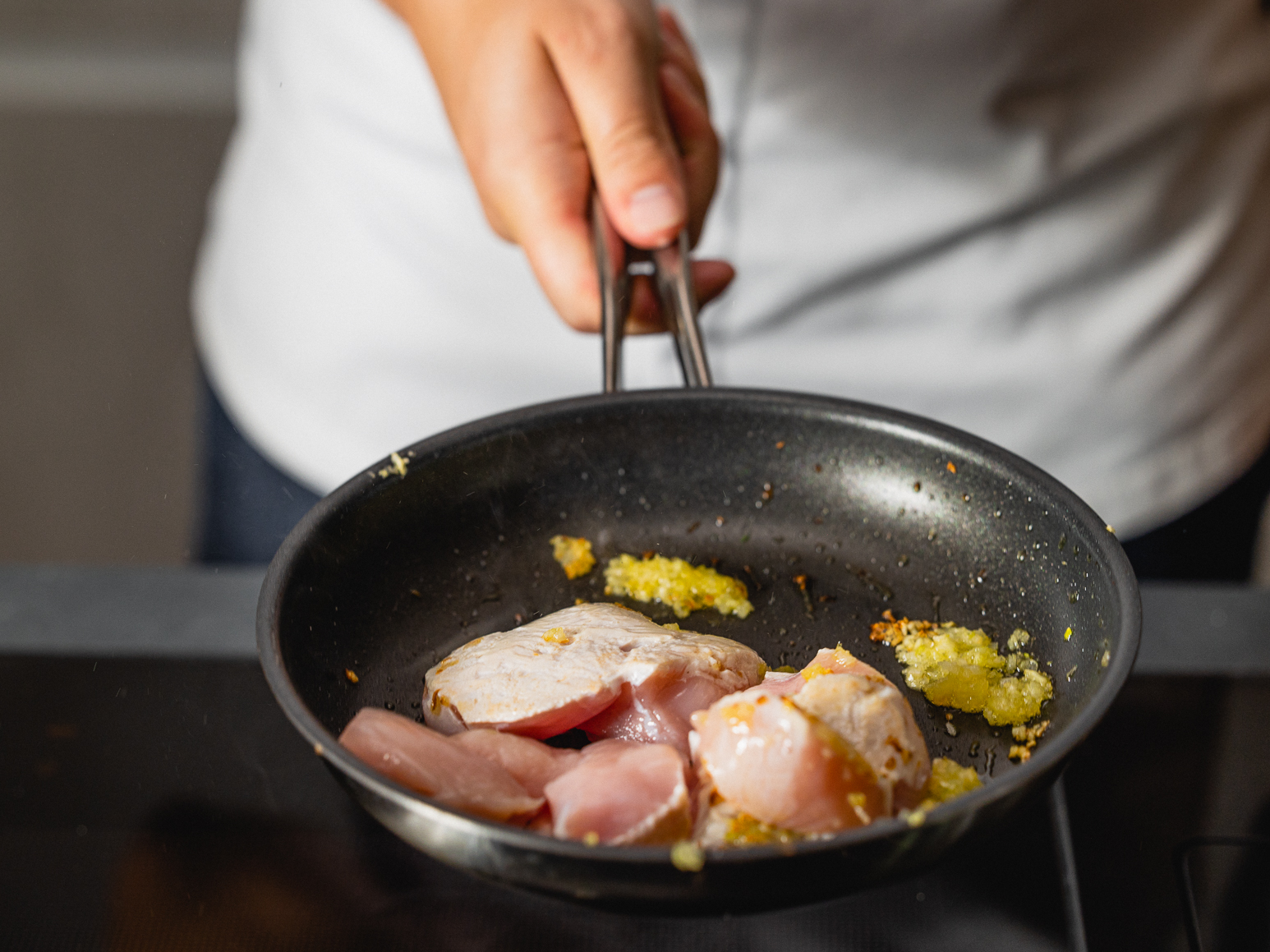 Schritt 2: Die Pouletstücke und die Paprikawürfel nun zu den Zwiebeln und dem Knoblauch in die Pfanne geben. 