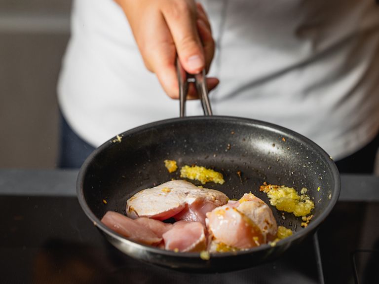 Schritt 2: Die Pouletstücke und die Paprikawürfel nun zu den Zwiebeln und dem Knoblauch in die Pfanne geben. Schritt 2: Die Pouletstücke und die Paprikawürfel nun zu den Zwiebeln und dem Knoblauch in die Pfanne geben.