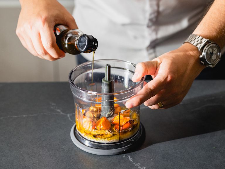 Schritt 2: Die gerösteten Karotten, den Knoblauch und den Ingwer in einen Mixer geben und zusammen mit dem Zitronensaft und der -schale, den gerösteten Wal- und Haselnüssen, dem Olivenöl und dem Sesamöl pürieren, bis eine cremige Paste entsteht Schritt 2: Die gerösteten Karotten, den Knoblauch und den Ingwer in einen Mixer geben und zusammen mit dem Zitronensaft und der -schale, den gerösteten Wal- und Haselnüssen, dem Olivenöl und dem Sesamöl pürieren, bis eine cremige Paste entsteht