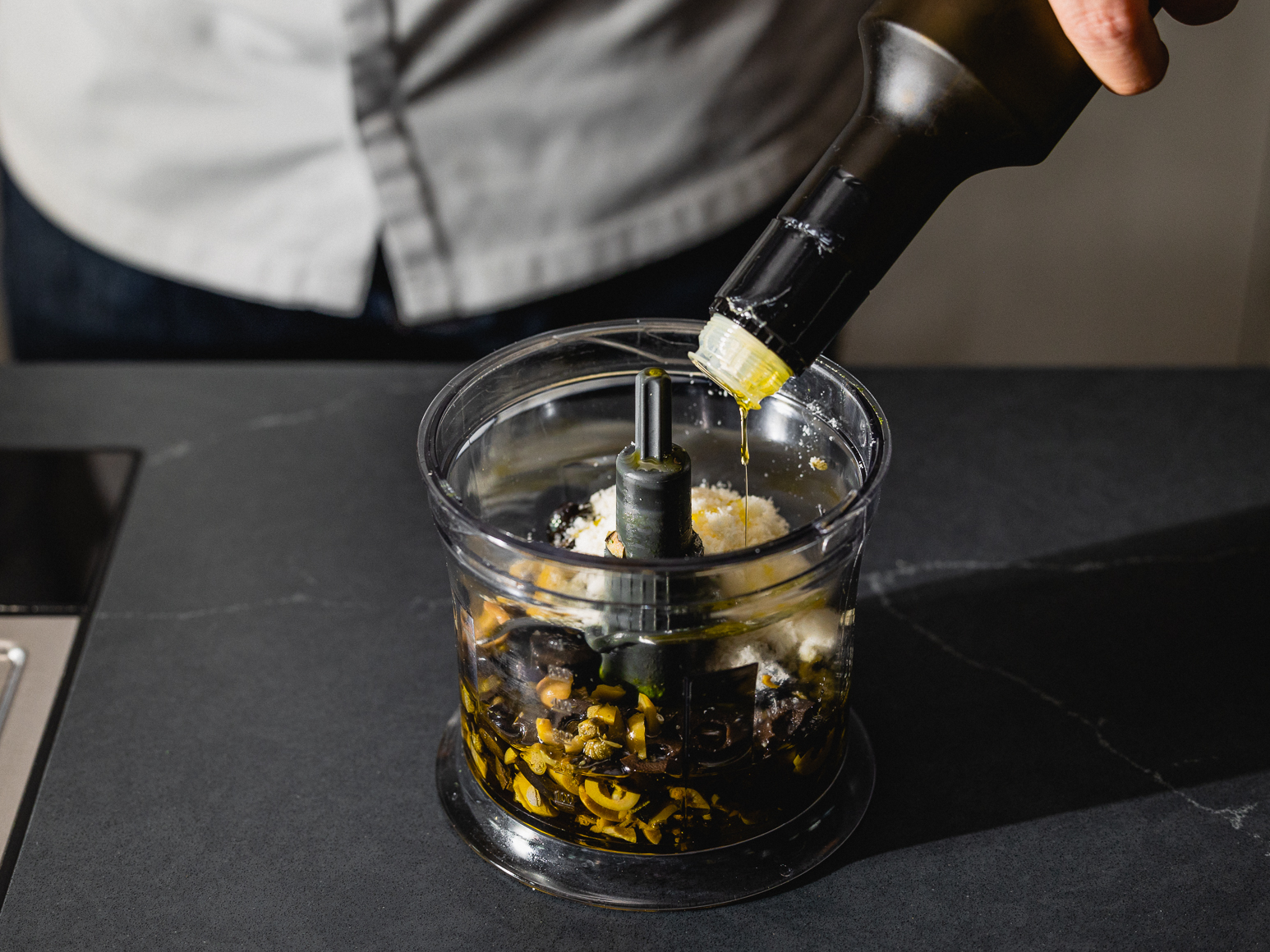 Schritt 1: Die gehackten Oliven, den gehackten Knoblauch, die gehackten Kapern, die gerösteten Zedernkerne, den geriebenen Parmesan und das Olivenöl in einen Mixer oder eine Küchenmaschine geben