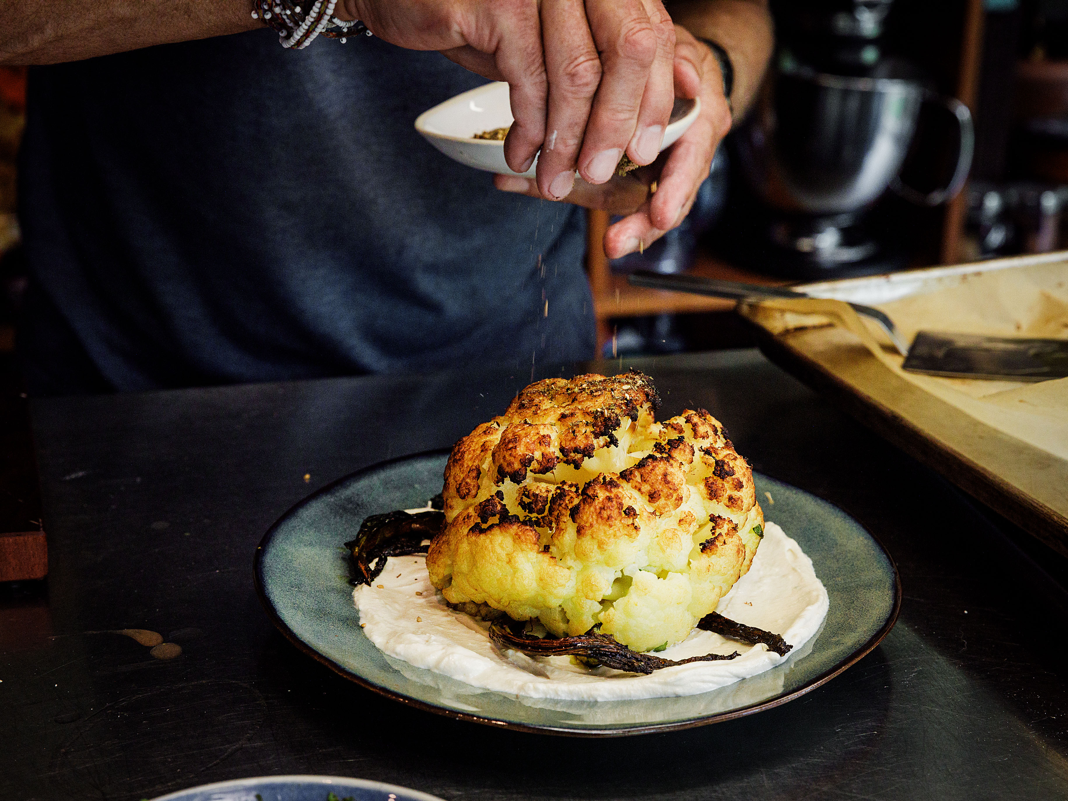 Schritt 3: Die Joghurt-Tahin-Sauce auf einem grossen Teller verteilen, den Blumenkohl darauf anrichten und mit Dukkah bestreuen