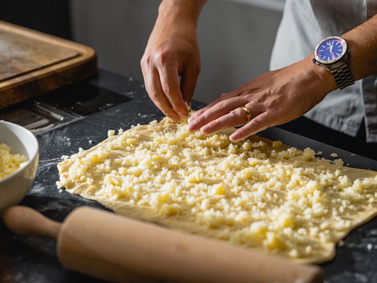 Schritt 1: Den Teig für Kokos-Zopf auf einer bemehlten Arbeitsfläche zu einem Rechteck ausrollen und die Füllung darauf verteilen. Schritt 1: Den Teig für Kokos-Zopf auf einer bemehlten Arbeitsfläche zu einem Rechteck ausrollen und die Füllung darauf verteilen.