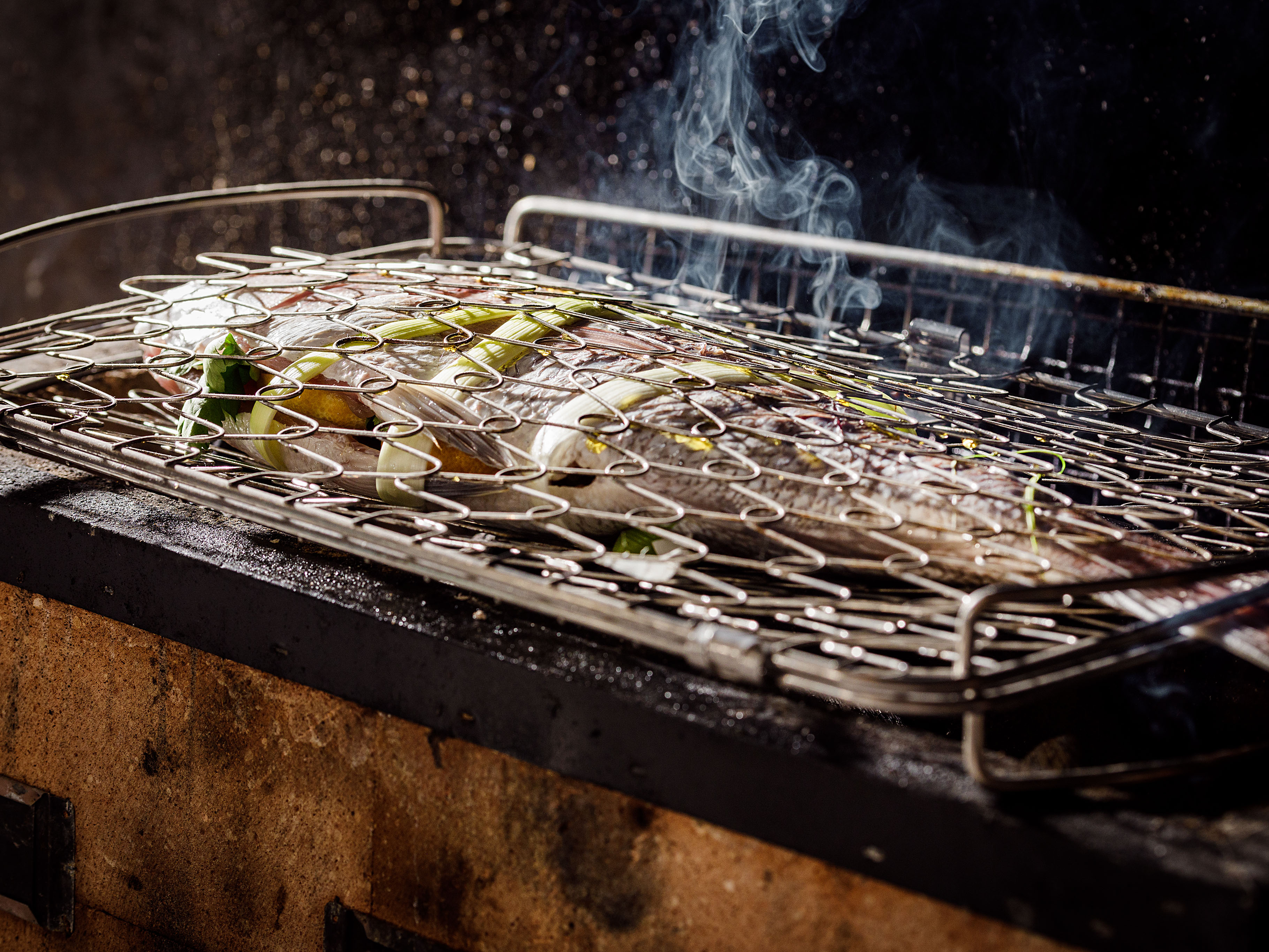 Schritt 3: Fisch in einen faltbaren Grillkorb legen und über der Glut auf beiden Seiten garen