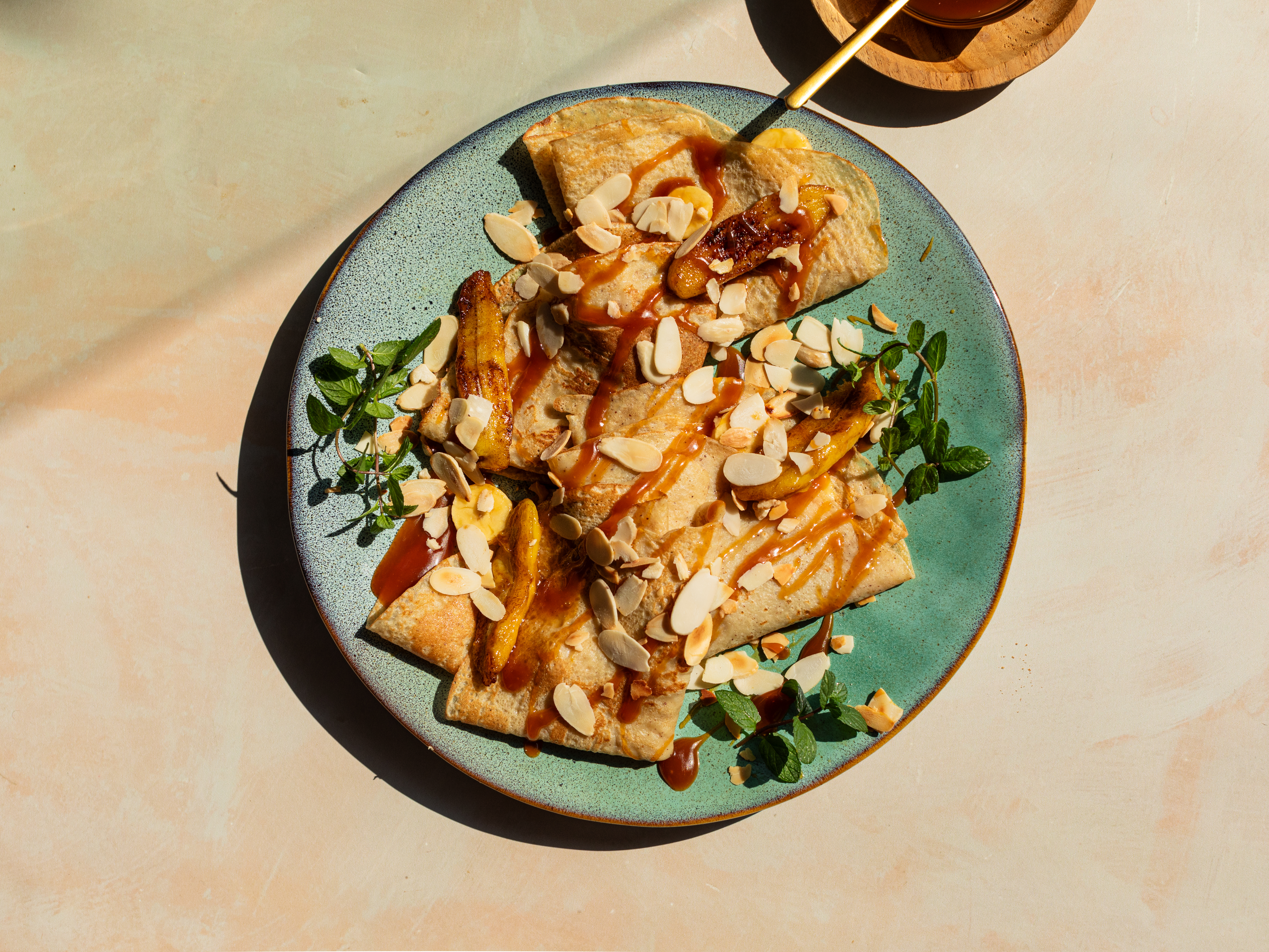 Schritt 6: Crêpes zusammenklappen auf einem Teller anrichten und mit den gebratenen Bananen, Mandeln und mehr Karamell garnieren und servieren