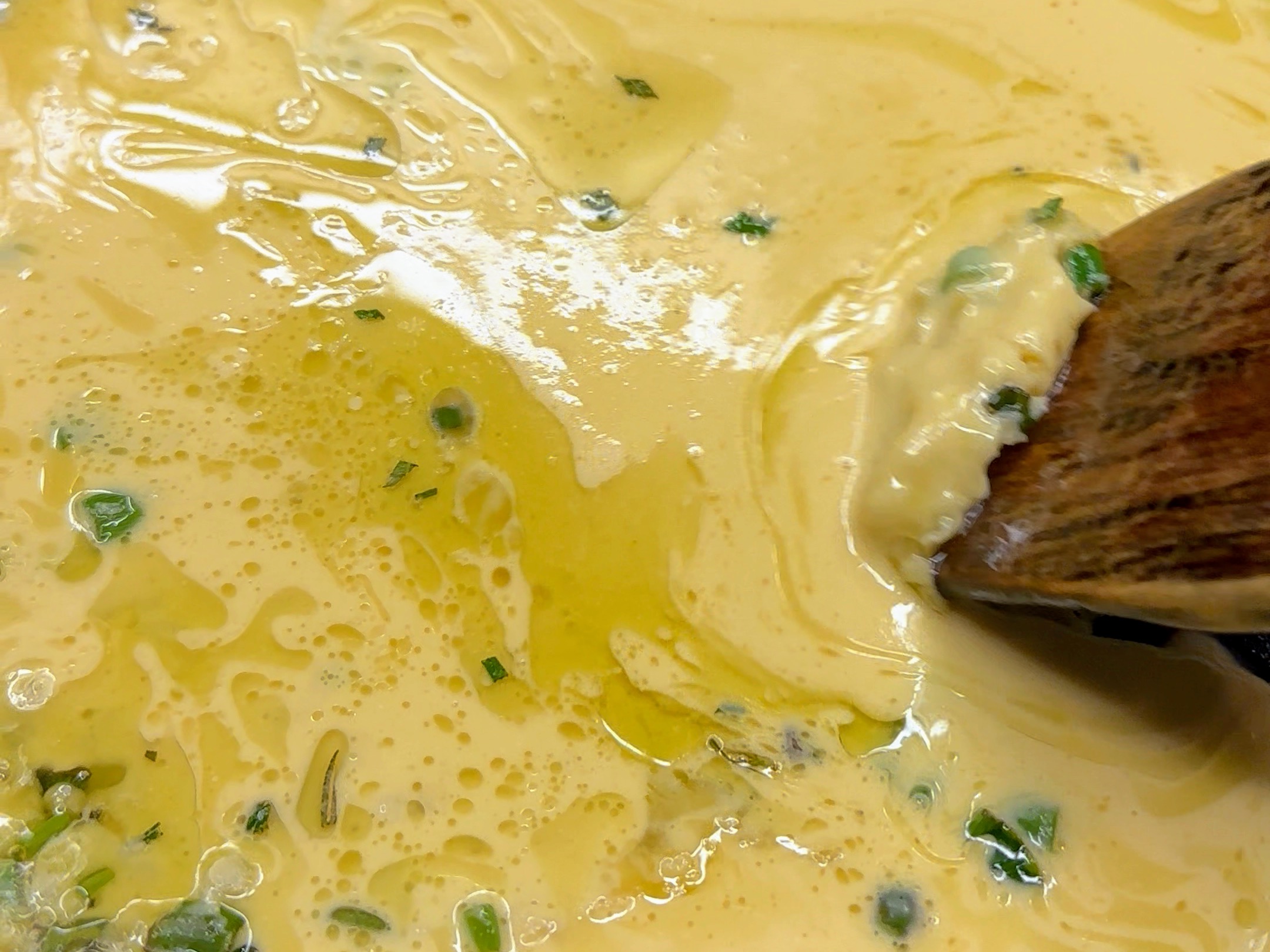 Schritt 3: Mit einem Holzspatel den Teig einmal vorsichtig durch die Pfanne ziehen, sodass ein Teil des Öls aufsteigt