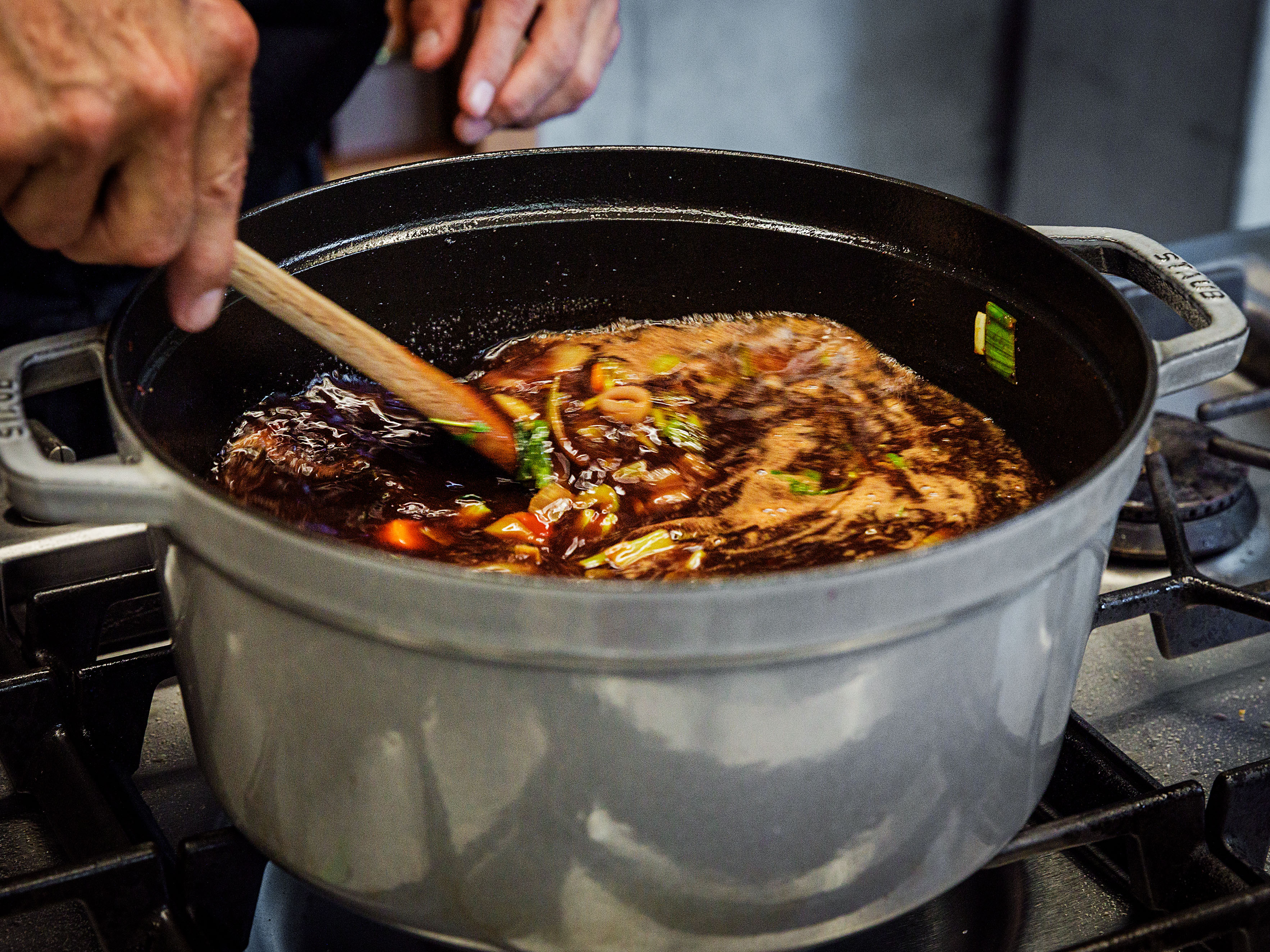 Schritt 3: Kalbsfuss-Scheiben zugeben, mit Rotwein und Portwein ablöschen, Gewürze und Kräuter zugeben und leicht einkochen lassen