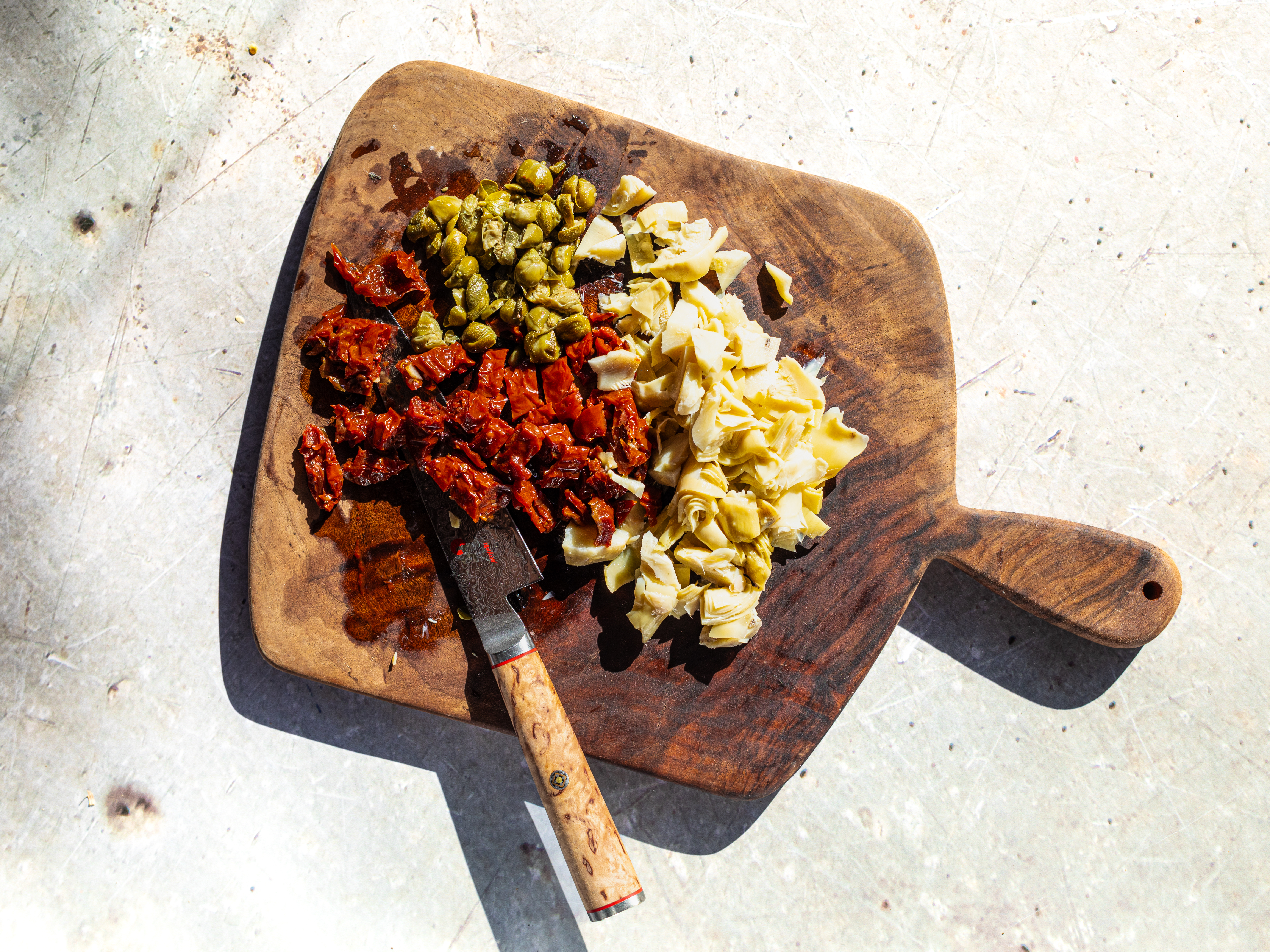 Schritt 2: Getrocknete Tomaten und Artischockenherzen in kleine Stücke schneiden. Die Kapern grob zerkleinern
