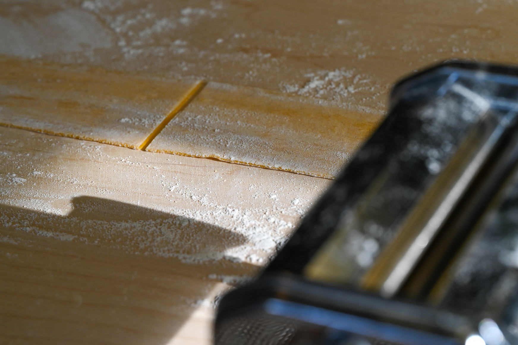 Schritt 3: Die einzelnen Teigstücke mit der Handfläche auf zirka einen halben Zentimeter flach drücken und in der Pastamaschine zu langen Teigblättern ausrollen