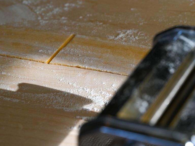 Schritt 3: Die einzelnen Teigstücke mit der Handfläche auf zirka einen halben Zentimeter flach drücken und in der Pastamaschine zu langen Teigblättern ausrollen