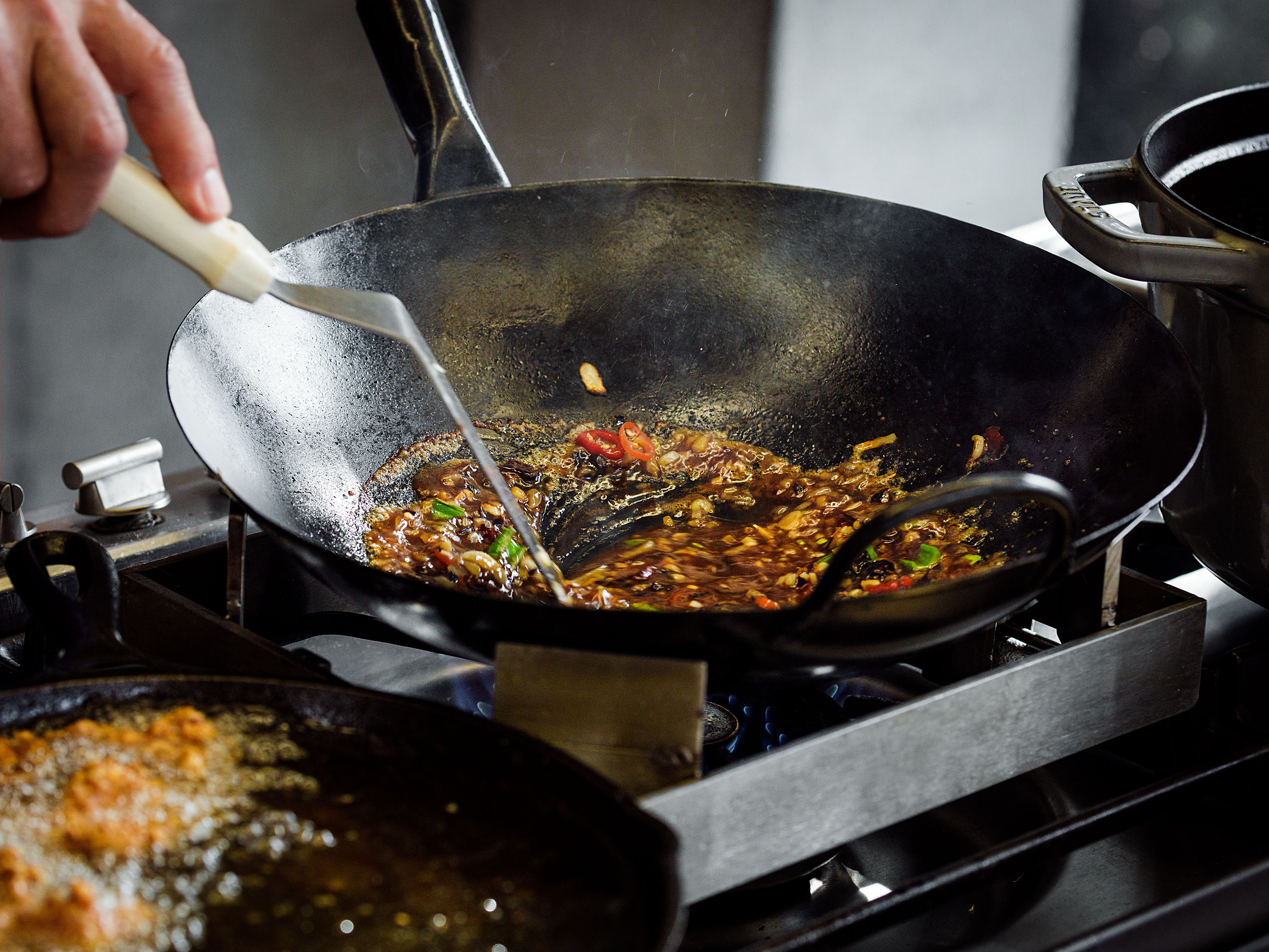 Schritt 5: Erdnuss- oder Rapsöl, Knoblauch, Ingwer, weisse Frühlingszwiebeln und Peperoncini in einen Wok oder eine grosse Pfanne geben und bei mittlerer Hitze erhitzen.