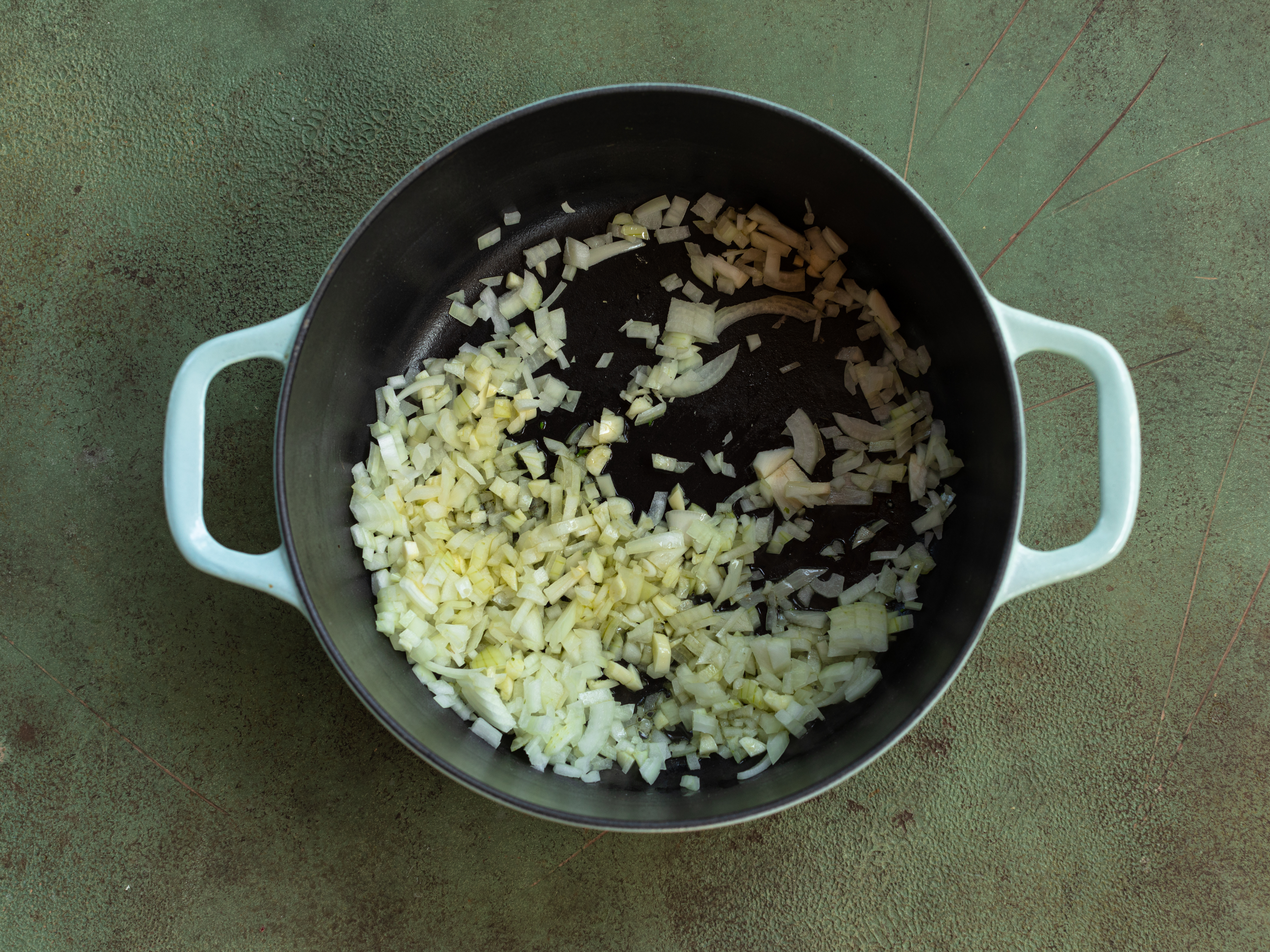 Schritt 1: In einem grossen Topf oder Bräter das Olivenöl erhitzen und die gewürfelte Zwiebel darin glasig dünsten und den gehackten Knoblauch hinzufügen und kurz anbraten