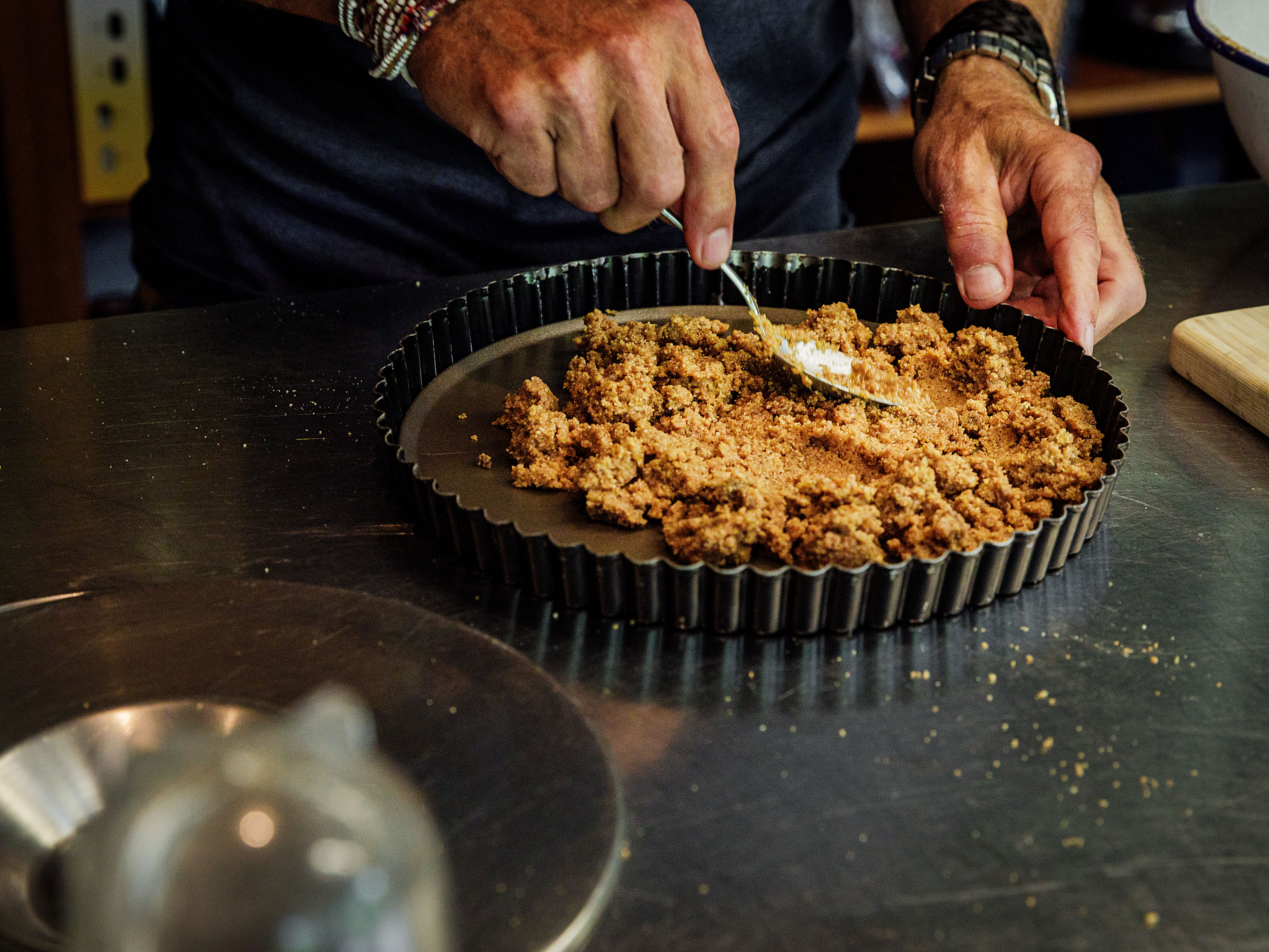 Schritt 1: Den Teig in eine Springform oder eine Tarteform mit herausnehmbarem Boden geben und festdrücken, sodass der Krümelteig eine feste Schicht auf dem Boden und an den Seiten der Form bildet