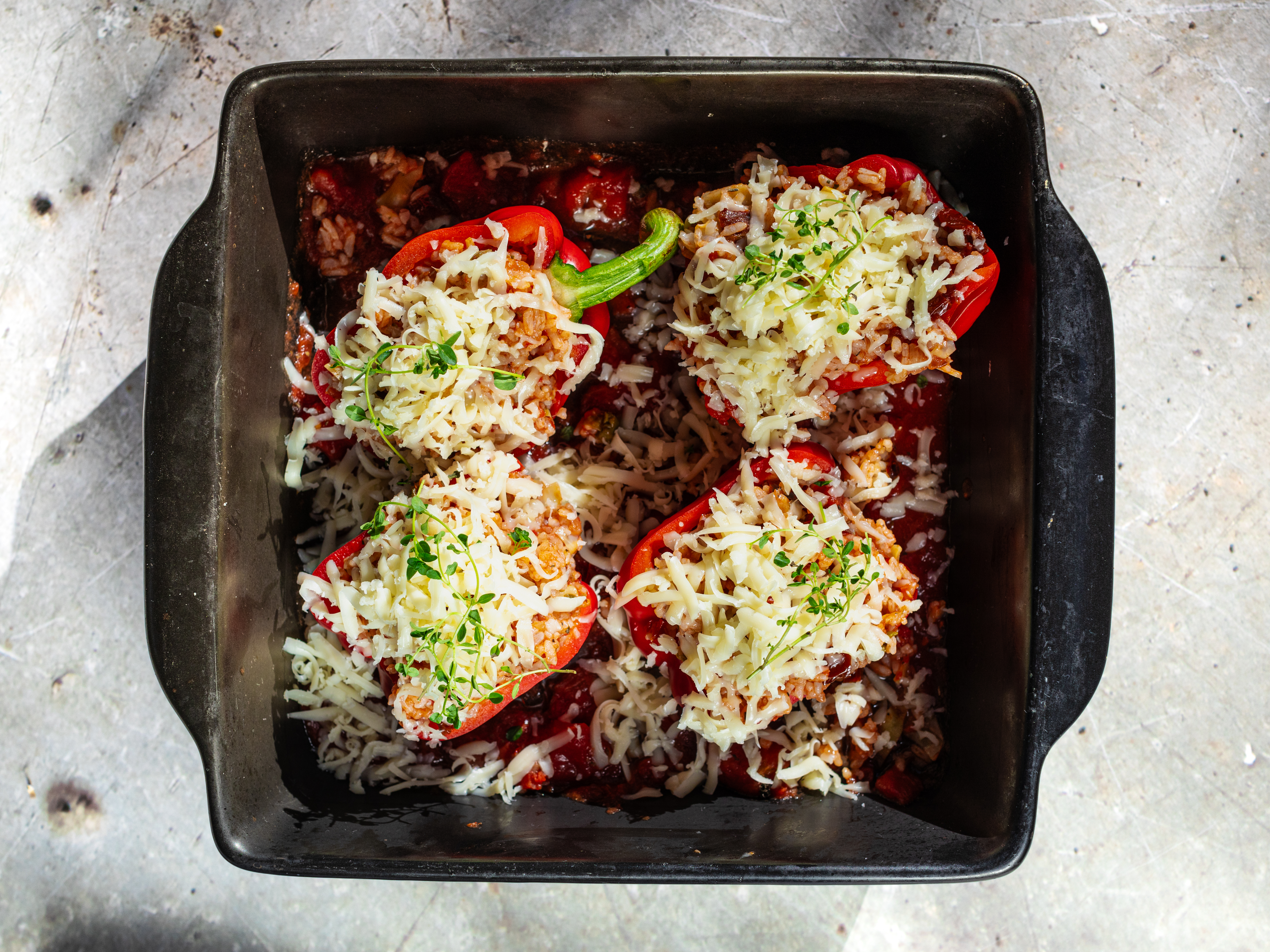 Schritt 4: Den geriebenen Käse gleichmässig über die gefüllten Peperoni streuen und backen, bis die Peperoni weich sind und der Käse goldbraun