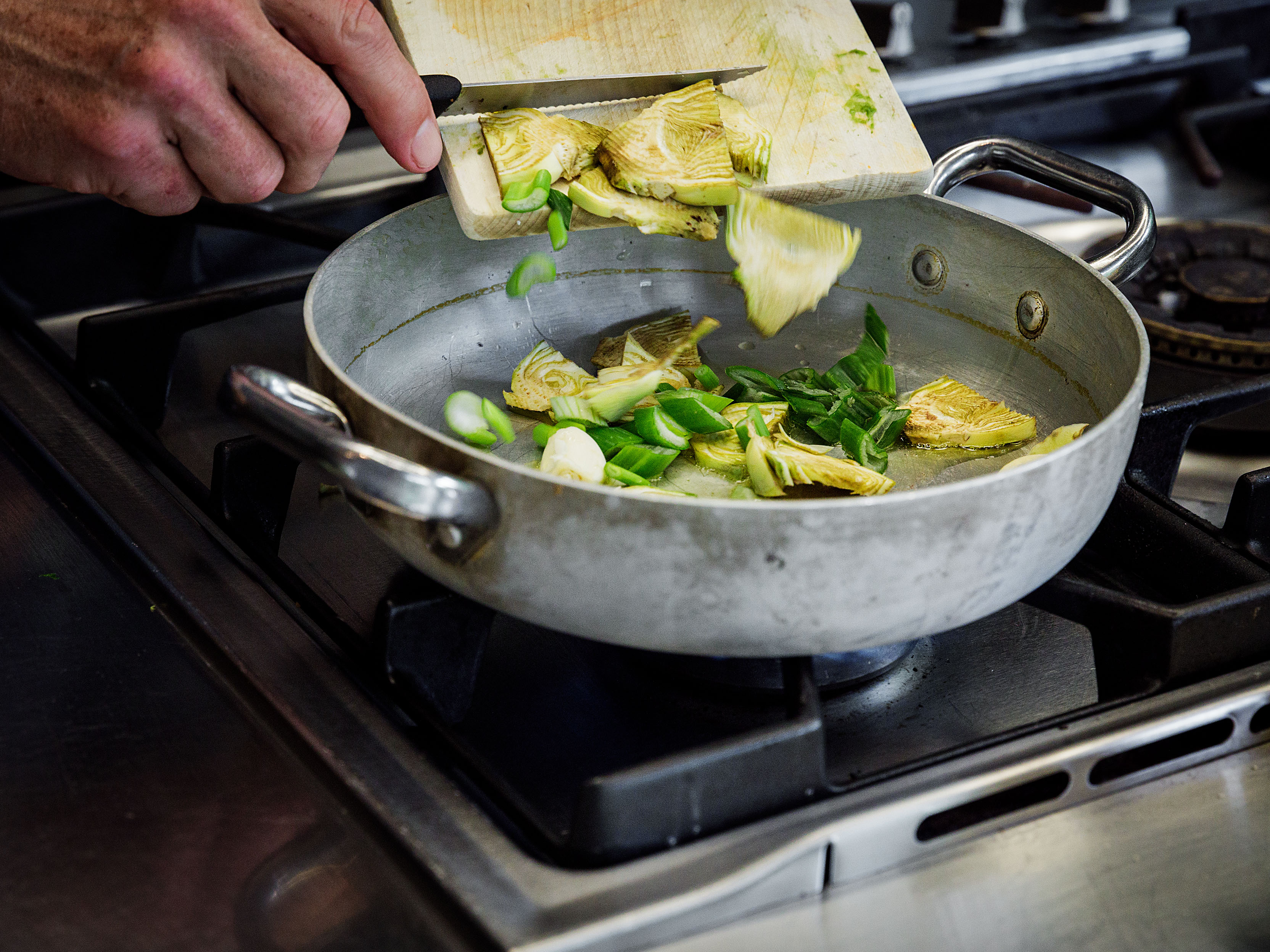Schritt 1: Die in Scheiben geschnittenen Artischocken, den Knoblauch und die Chilischote in das Öl hinzugeben und braten.