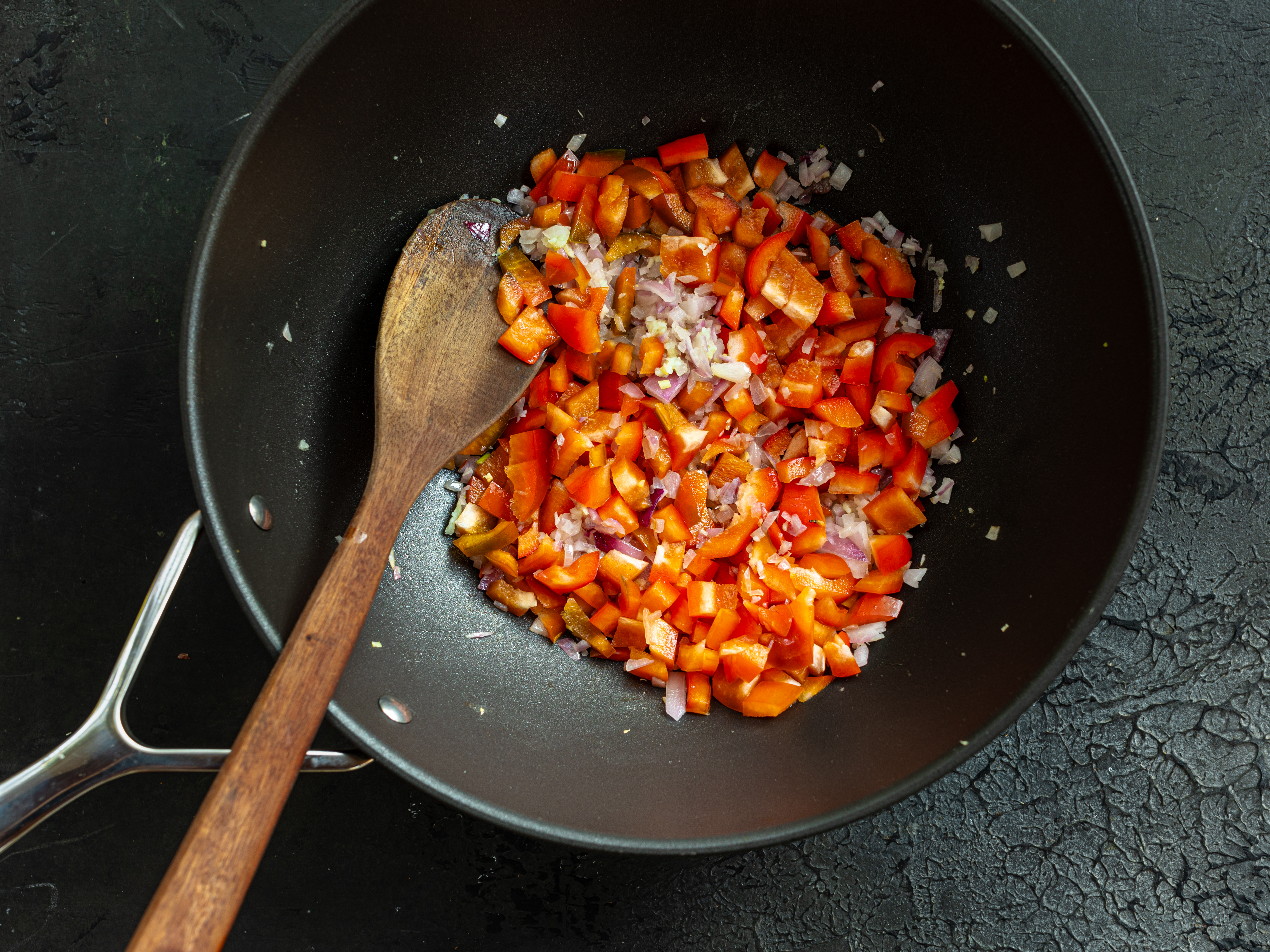 Schritt 1: In einer grossen Pfanne das Olivenöl erhitzen, Zwiebeln und Knoblauch darin anschwitzen, bis sie weich werden, dann die Paprikawürfel hinzufügen