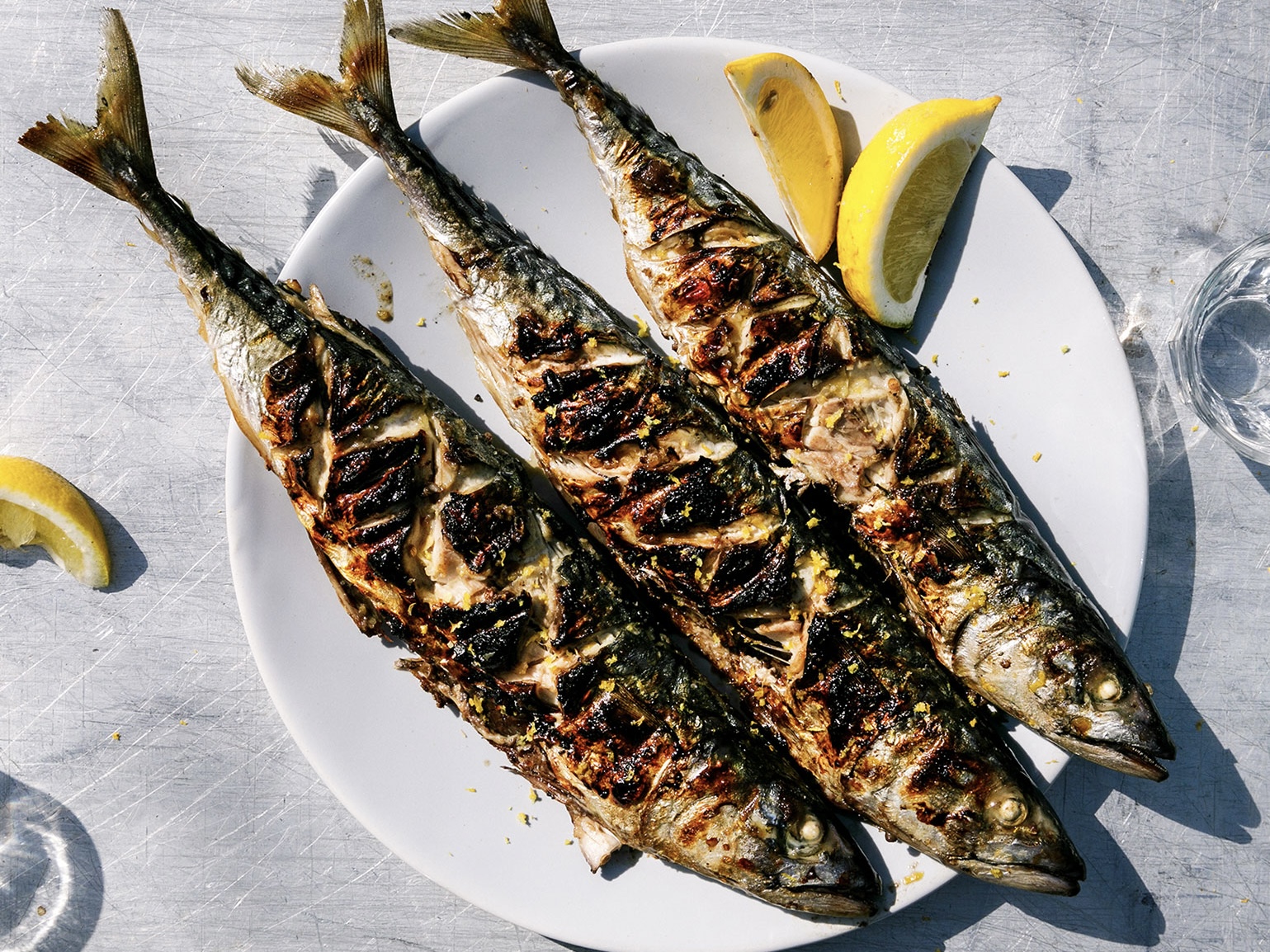 Schritt 3: Ganze Makrelen zusammen mit Zitronenschnitzen auf einem grossen Teller anrichten