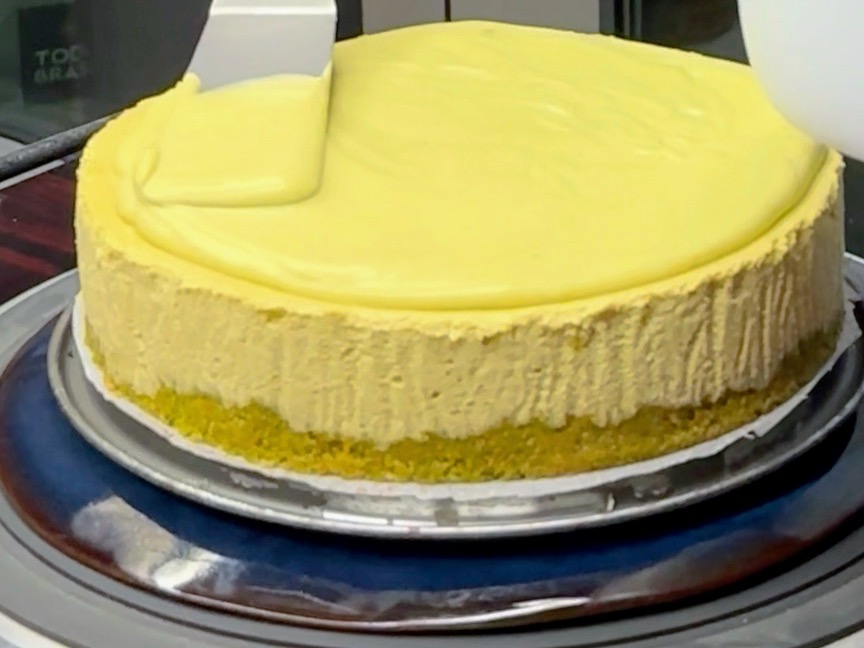 Schritt 5: Schokolade mit Doppelrahm im Wasserbad schmelzen, mit der restlichen Pistaziencreme verrühren und mit einem Spachtel auf dem Kuchen verteilen