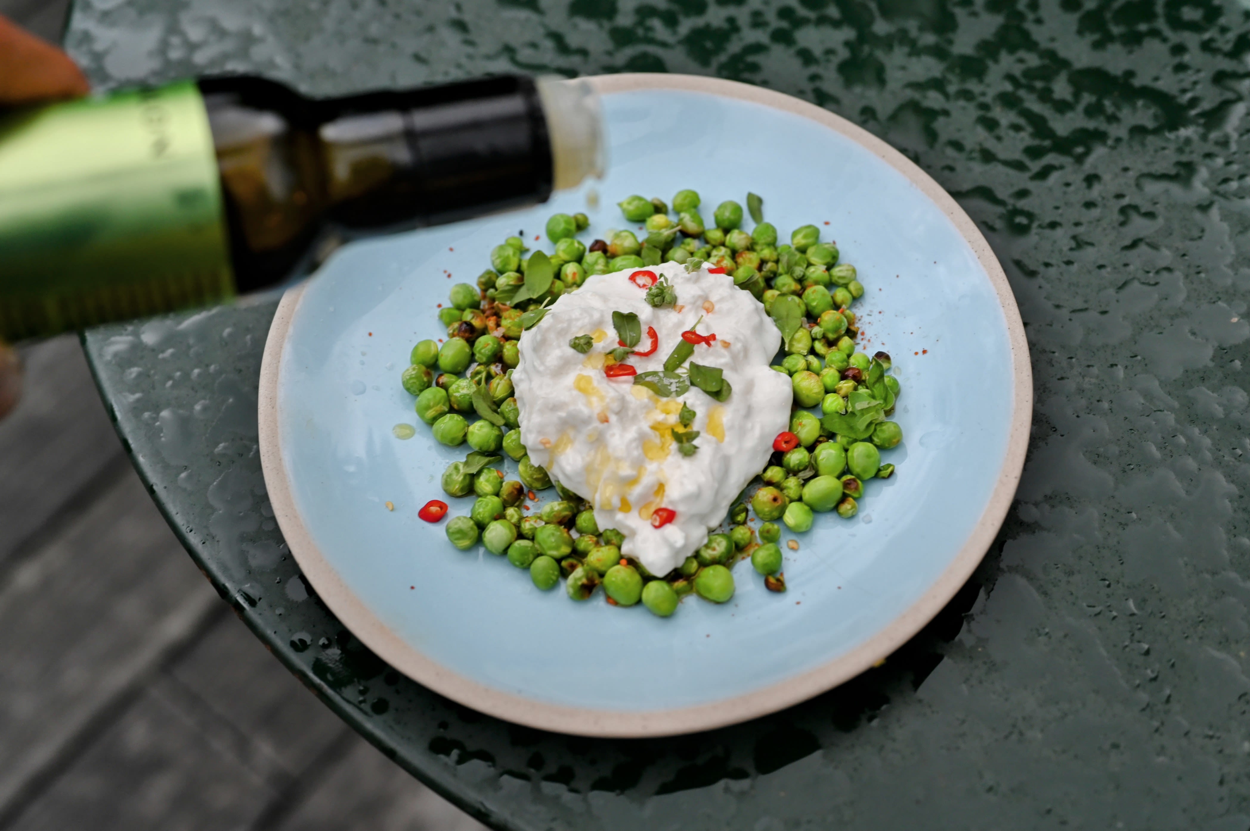 Schritt 3: Den Burrata darauf verteilen und mit den getrockneten Yuzu-Schalen, Chili-Streifen und Oreganoblättchen bestreuen. Mit Salz, Pfeffer und Togarashi würzen und Olivenöl nach Belieben beträufeln