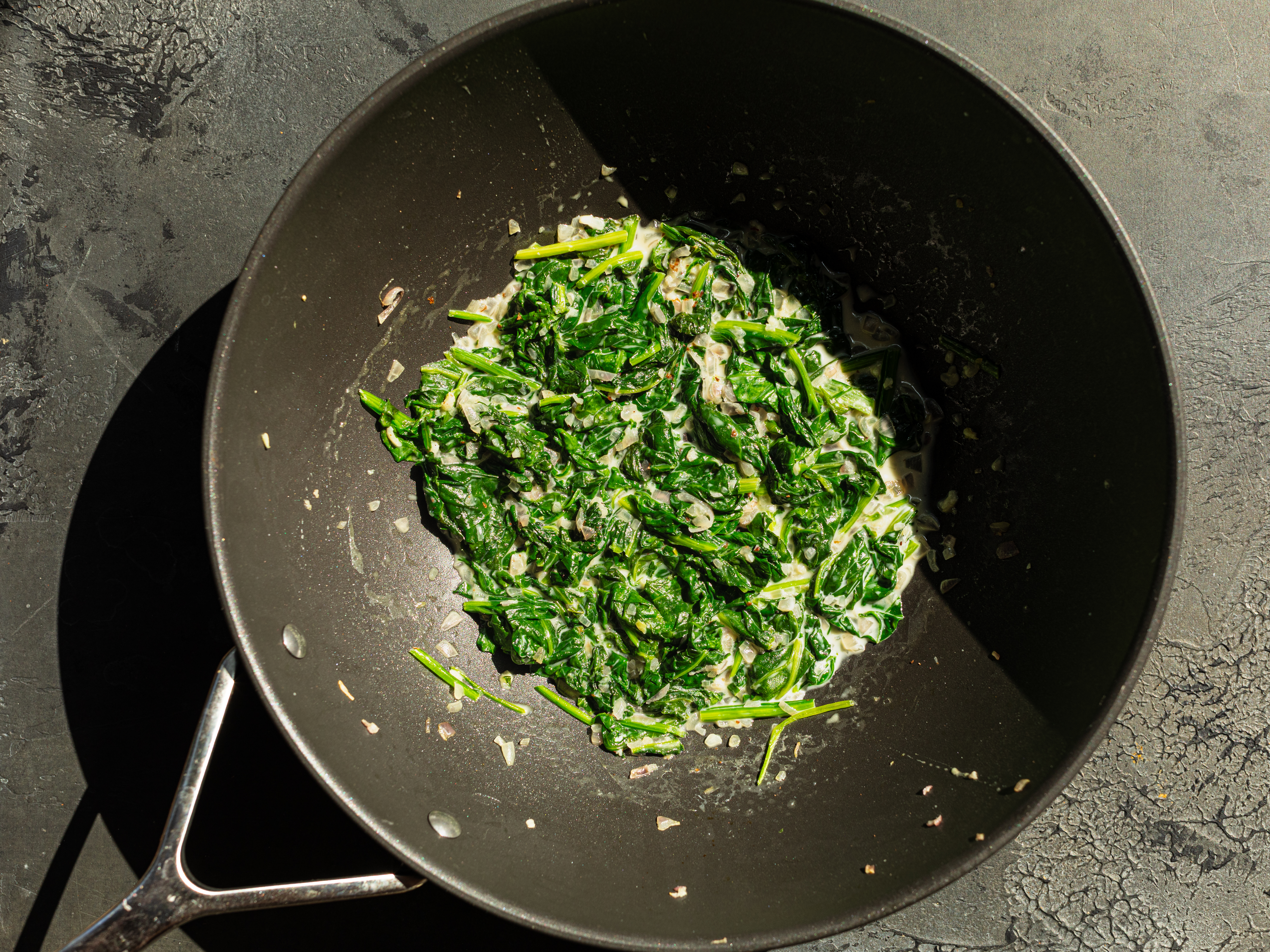 Schritt 2: Den frischen Spinat hinzufügen und kurz anbraten, bis er zusammenfällt