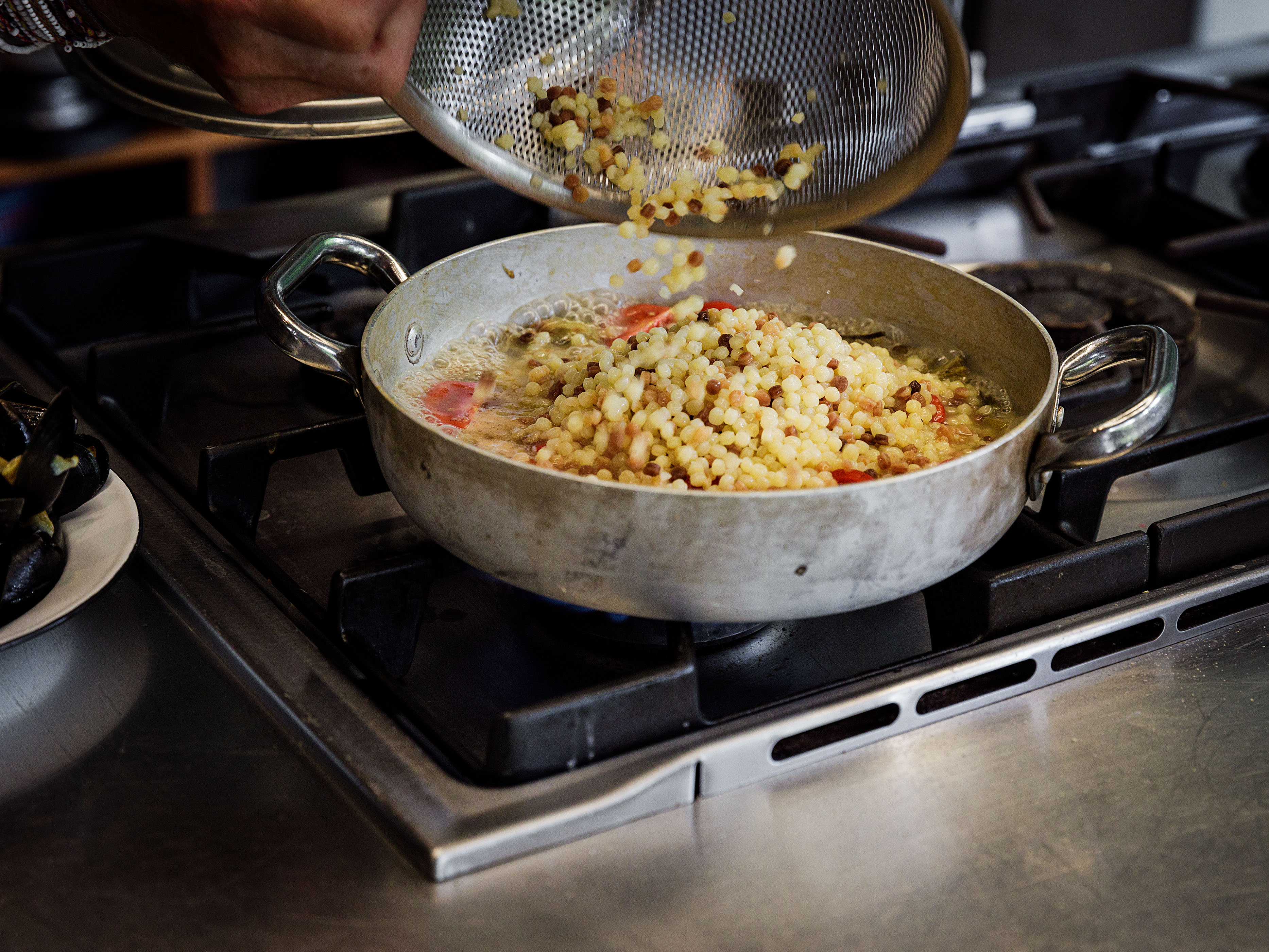 Schritt 3: Tomaten, Fischfond und Fregola in die Pfanne geben, umrühren und aufkochen