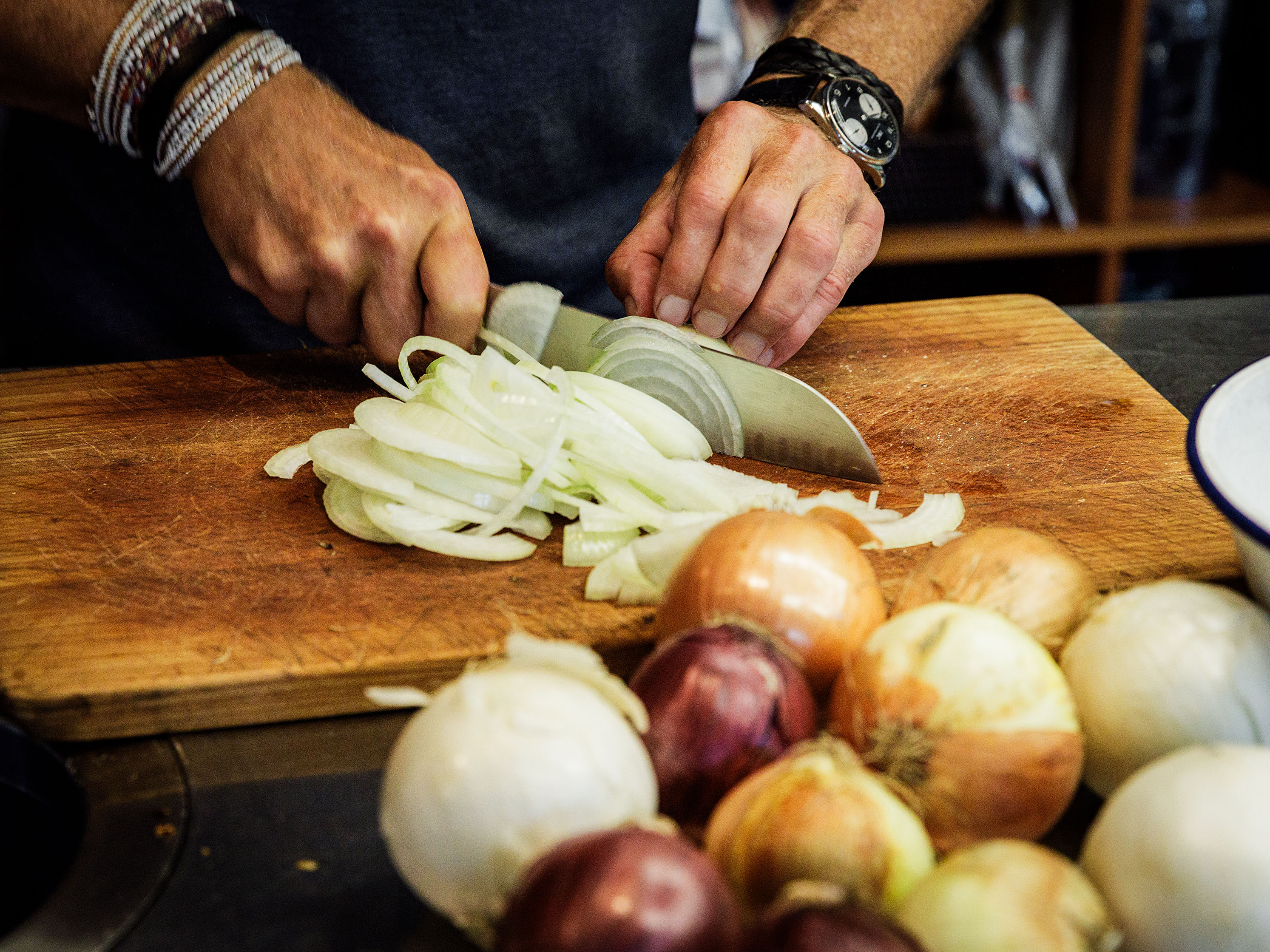 Schritt 3: Die Zwiebeln längs halbieren, dann schälen und längs in feine Streifen schneiden. 