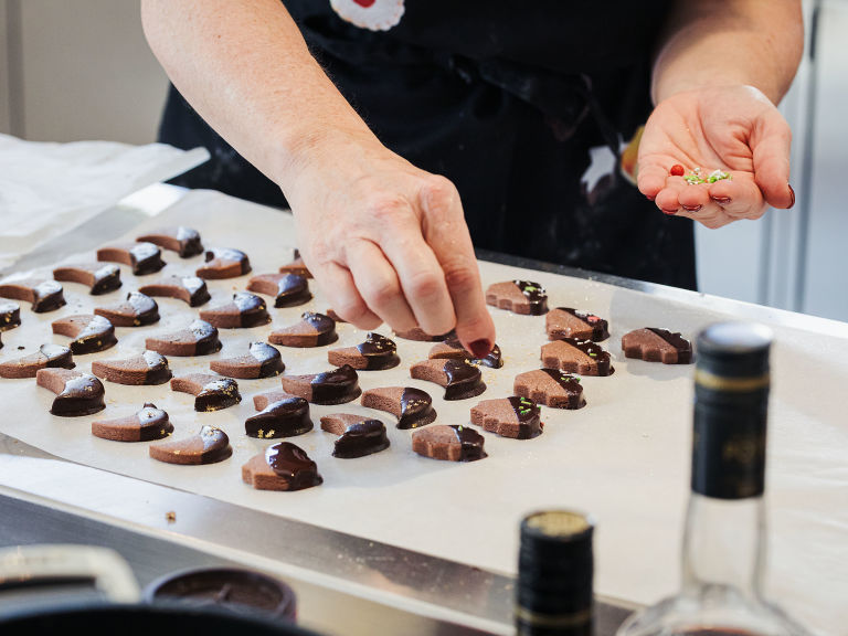 Schritt 3: Die Sablés glasieren und sofort, bevor die Schokolade fest wird, mit Zuckerperlen oder Zuckersternen dekorieren