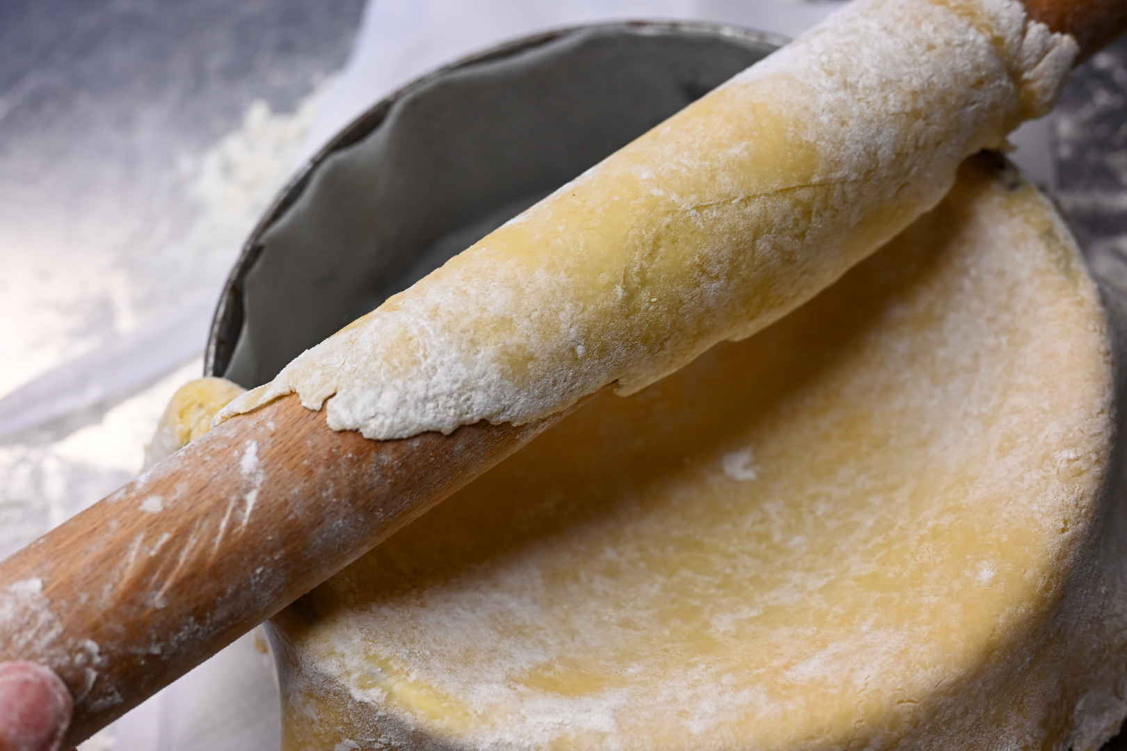 Schritt 2: Den Teig vorsichtig um ein bemehltes Wallholz wickeln, über die Form legen und locker ausrollen
