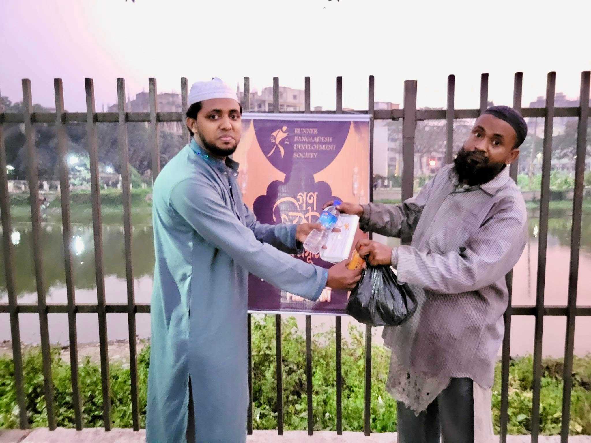 A volunteer hands an Iftar meal to a man, ensuring no one goes hungry during the holy month.