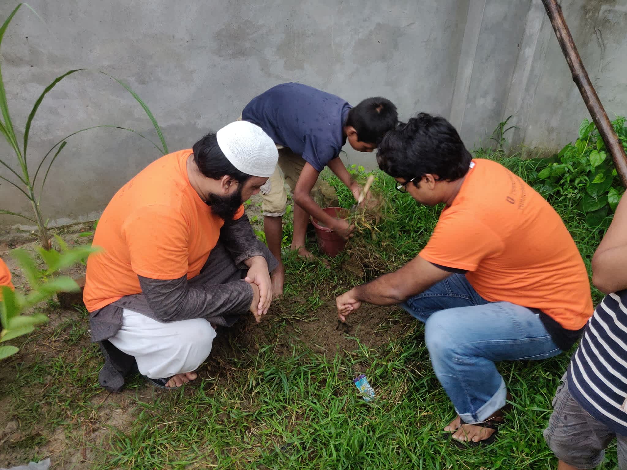 Student helping Runner Bangladesh members plant a tree during a tree-planting campaign
